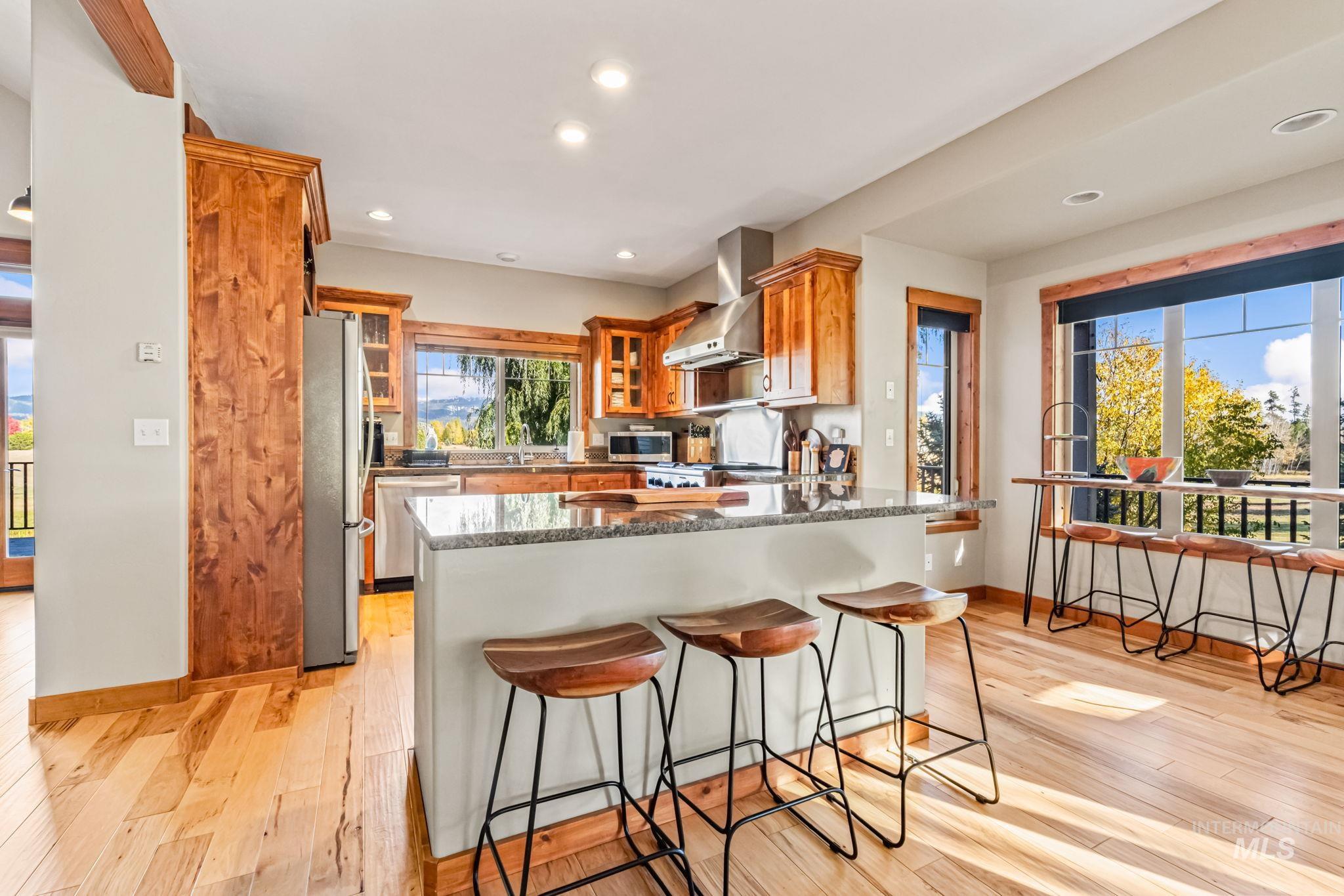 Kitchen with a peninsula, a breakfast bar area, brown cabinets, dark stone countertops, and recessed lighting