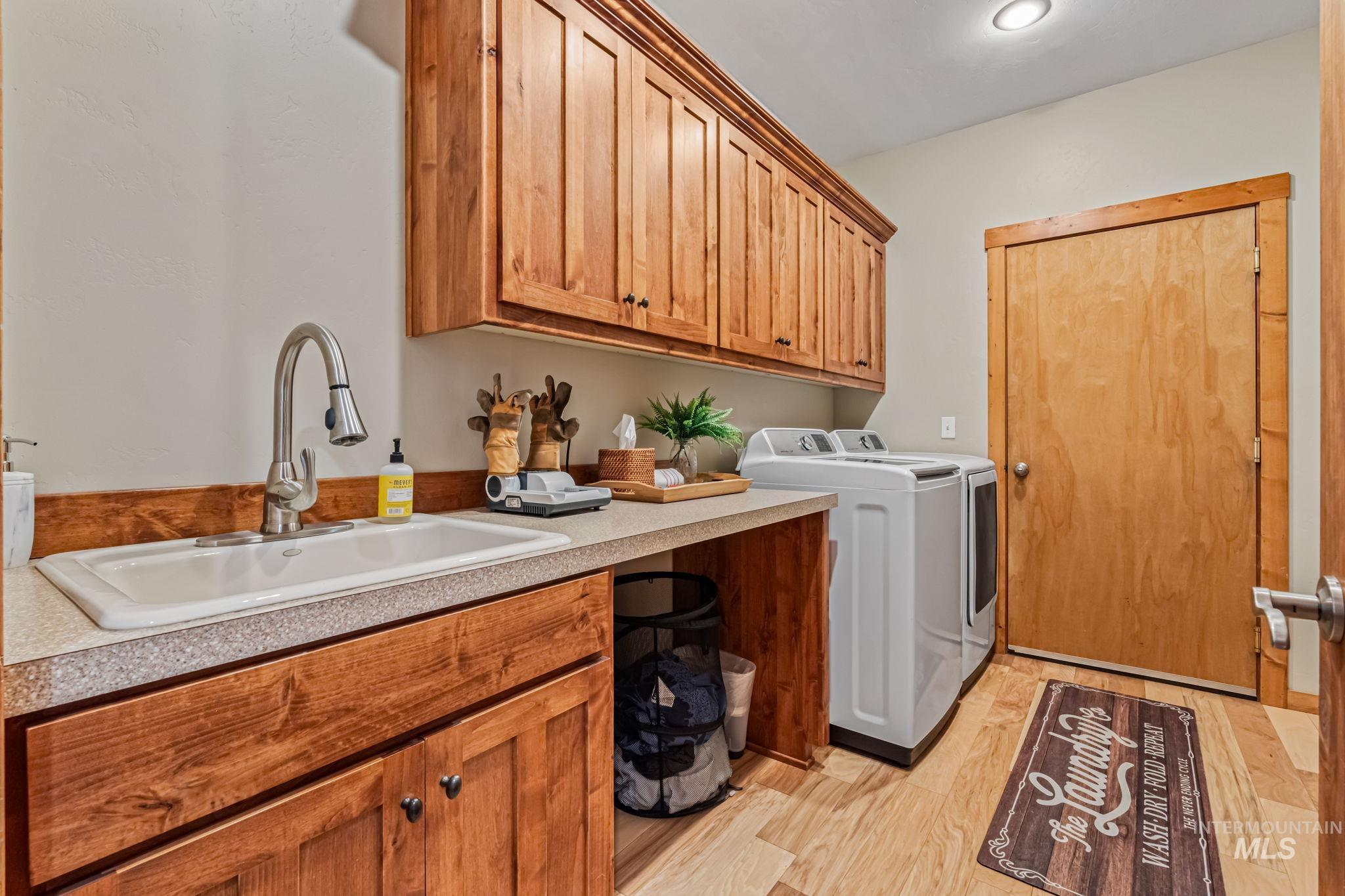 Laundry area with light wood-style flooring, independent washer and dryer, and cabinet space