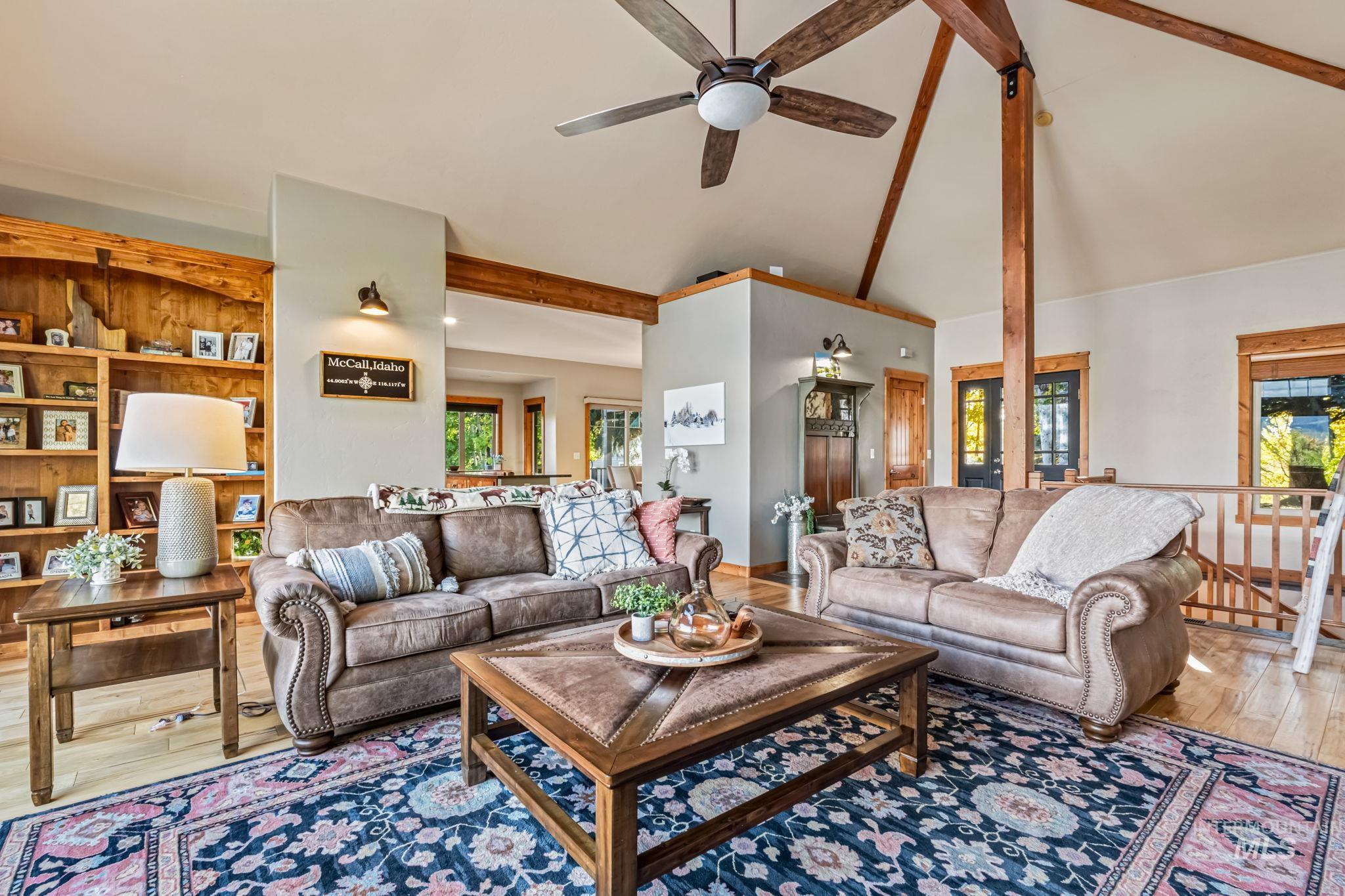 Living area featuring hardwood / wood-style floors, beam ceiling, high vaulted ceiling, and a ceiling fan