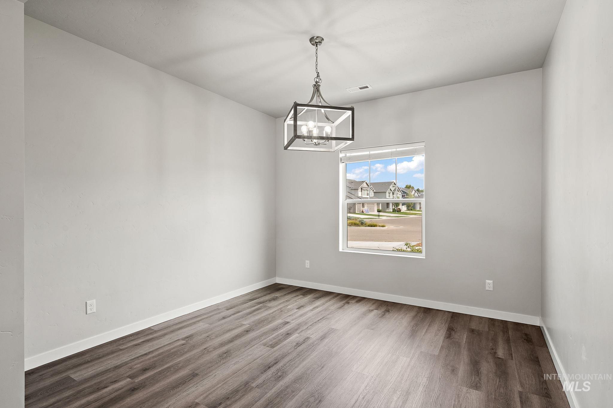 Unfurnished dining area featuring wood finished floors and a chandelier