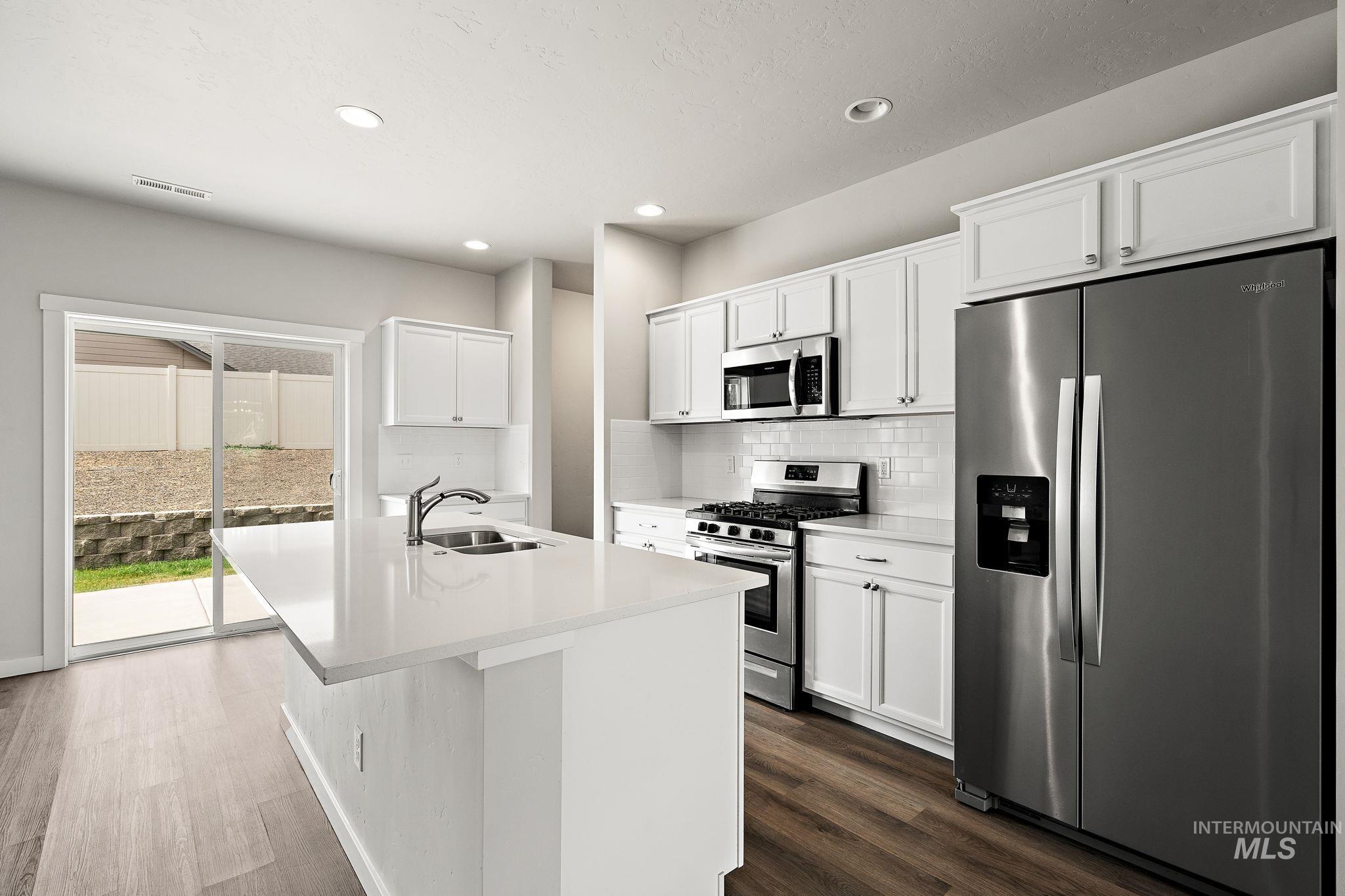 Kitchen with stainless steel appliances, white cabinetry, a kitchen island with sink, recessed lighting, and dark wood-type flooring