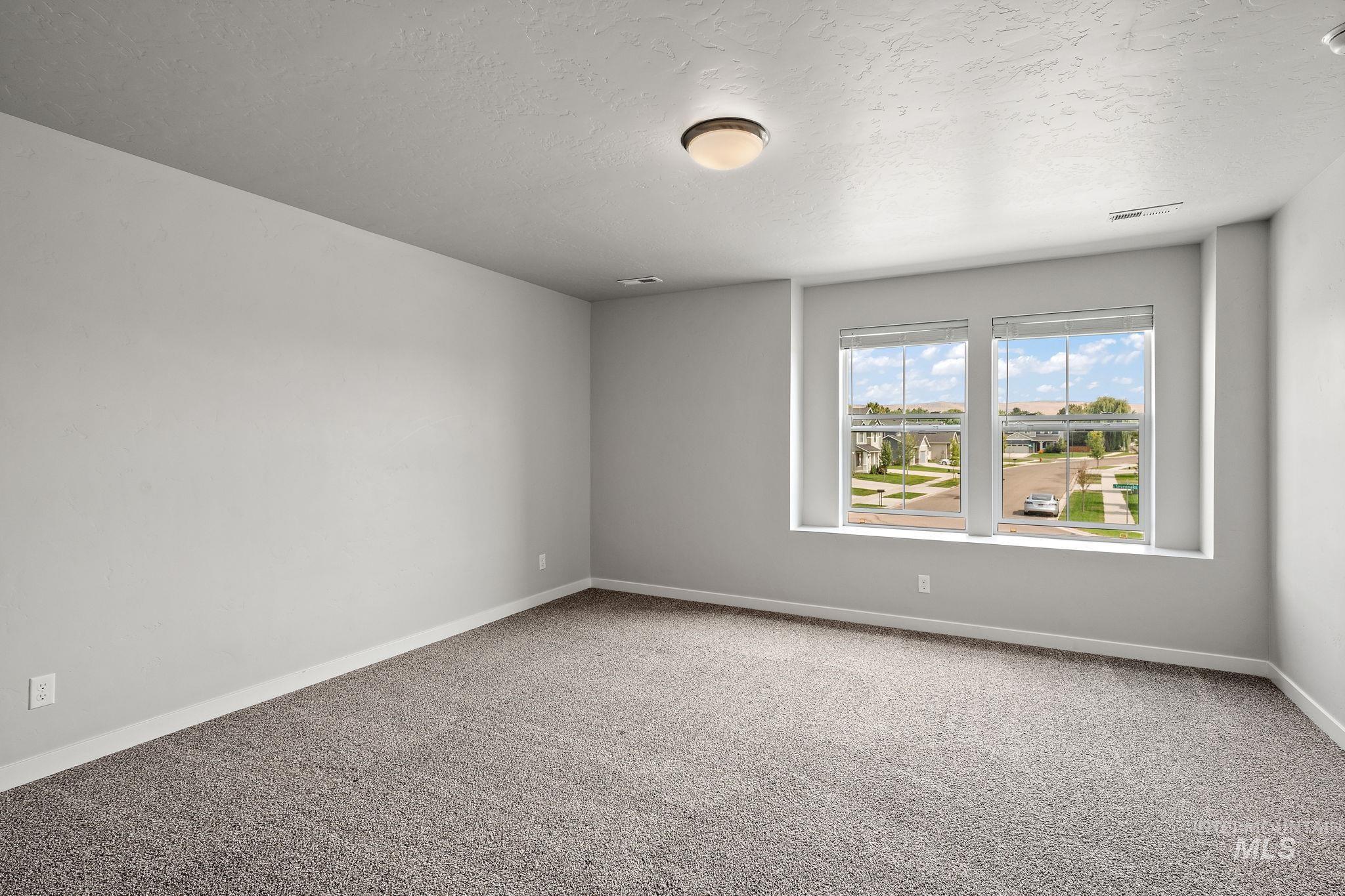 Empty room featuring a textured ceiling and light colored carpet