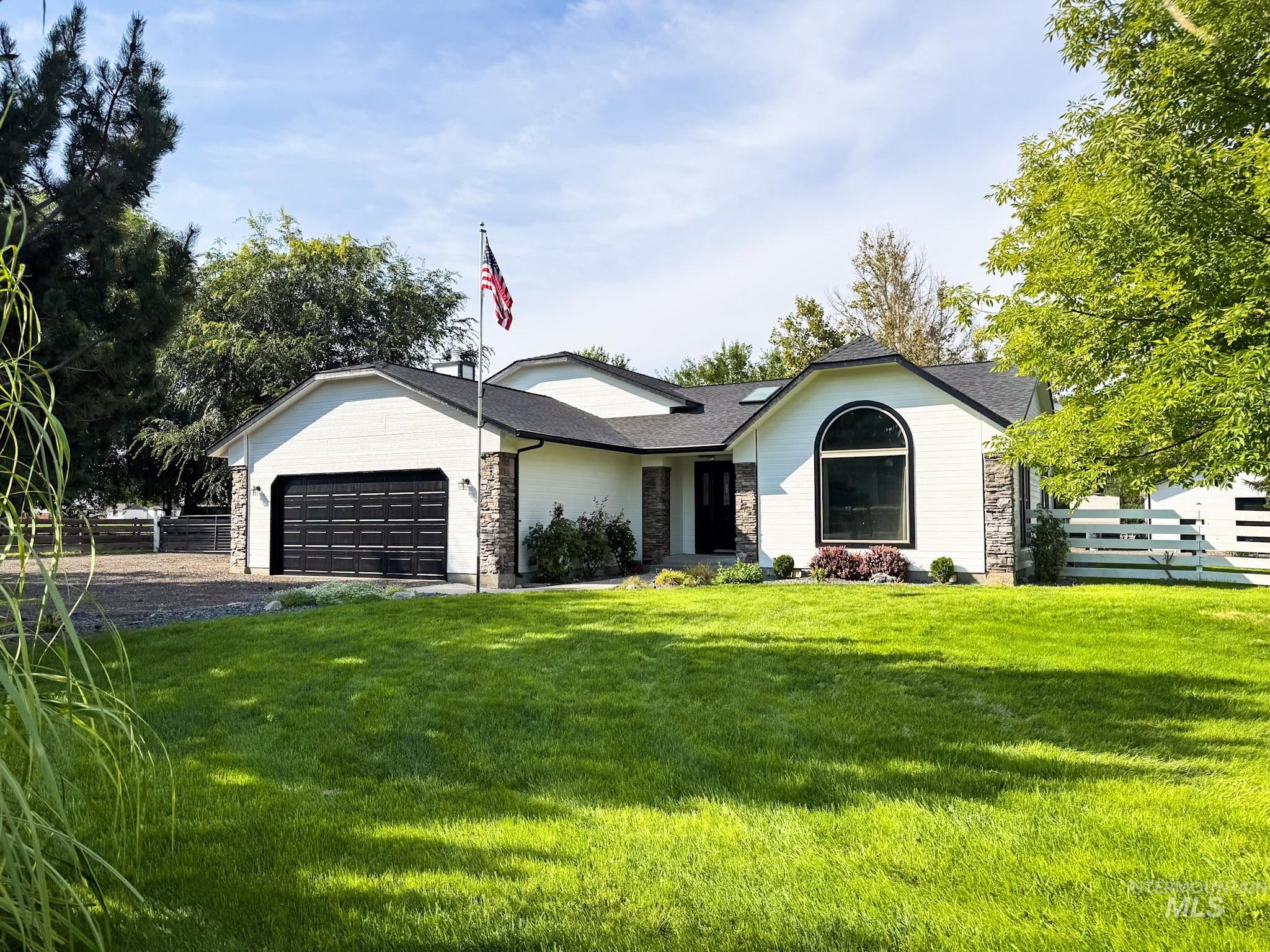 Ranch-style home featuring stone siding, an attached garage, driveway, and a shingled roof