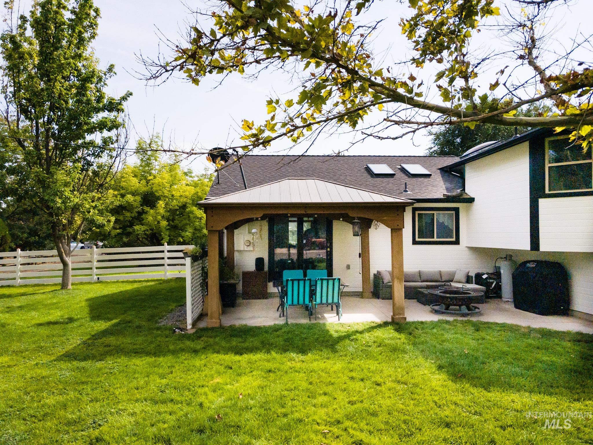 Rear view of property with a patio area, a fire pit, and roof with shingles