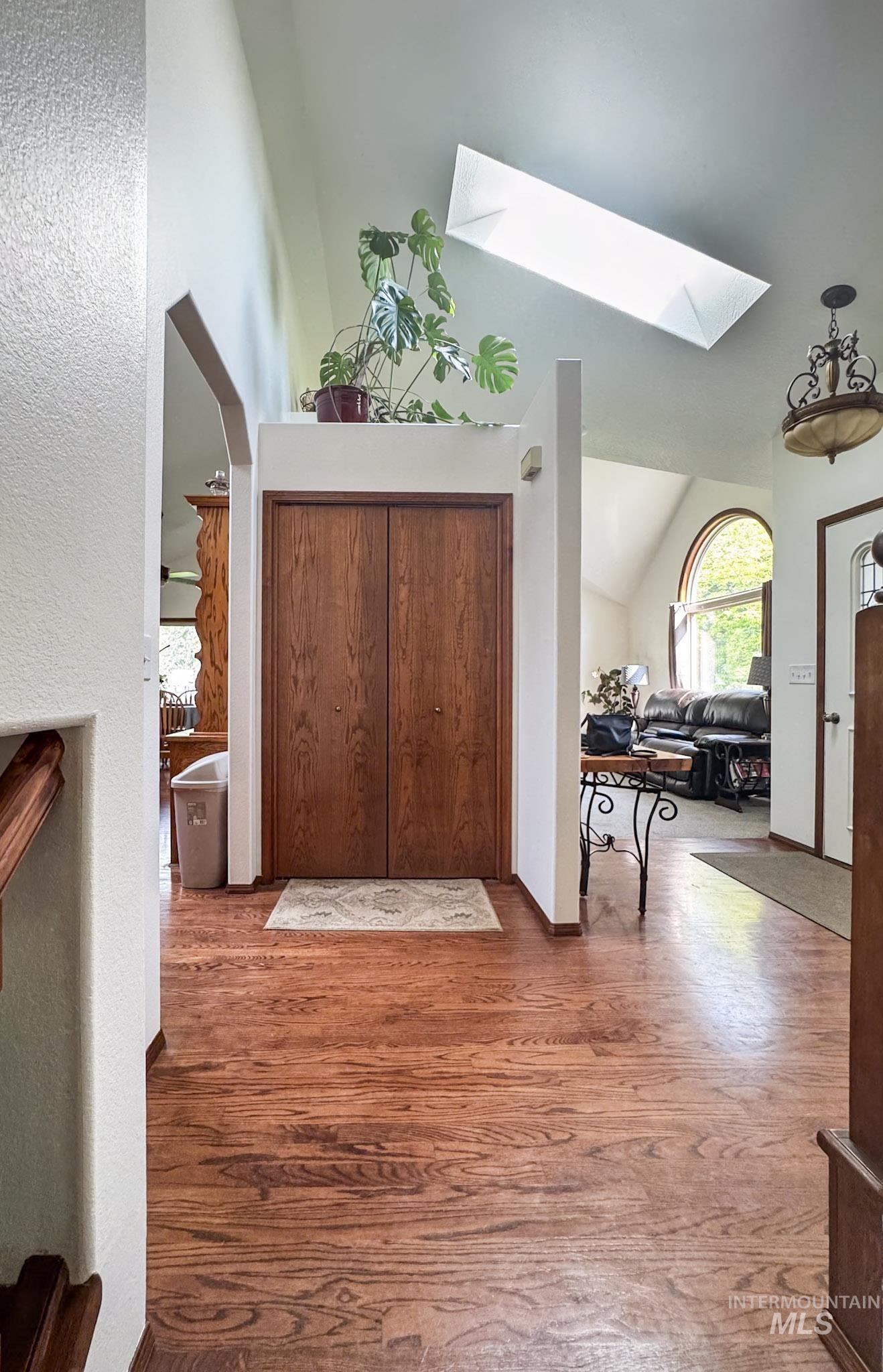 Entryway featuring wood finished floors, a skylight, and high vaulted ceiling