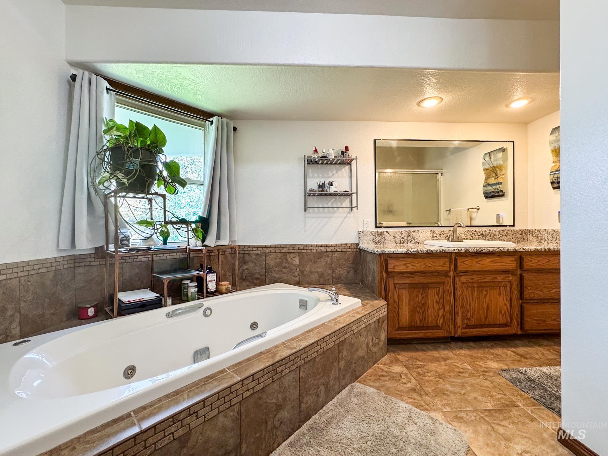 Bathroom with a jetted tub, vanity, a stall shower, a textured ceiling, and light tile patterned floors