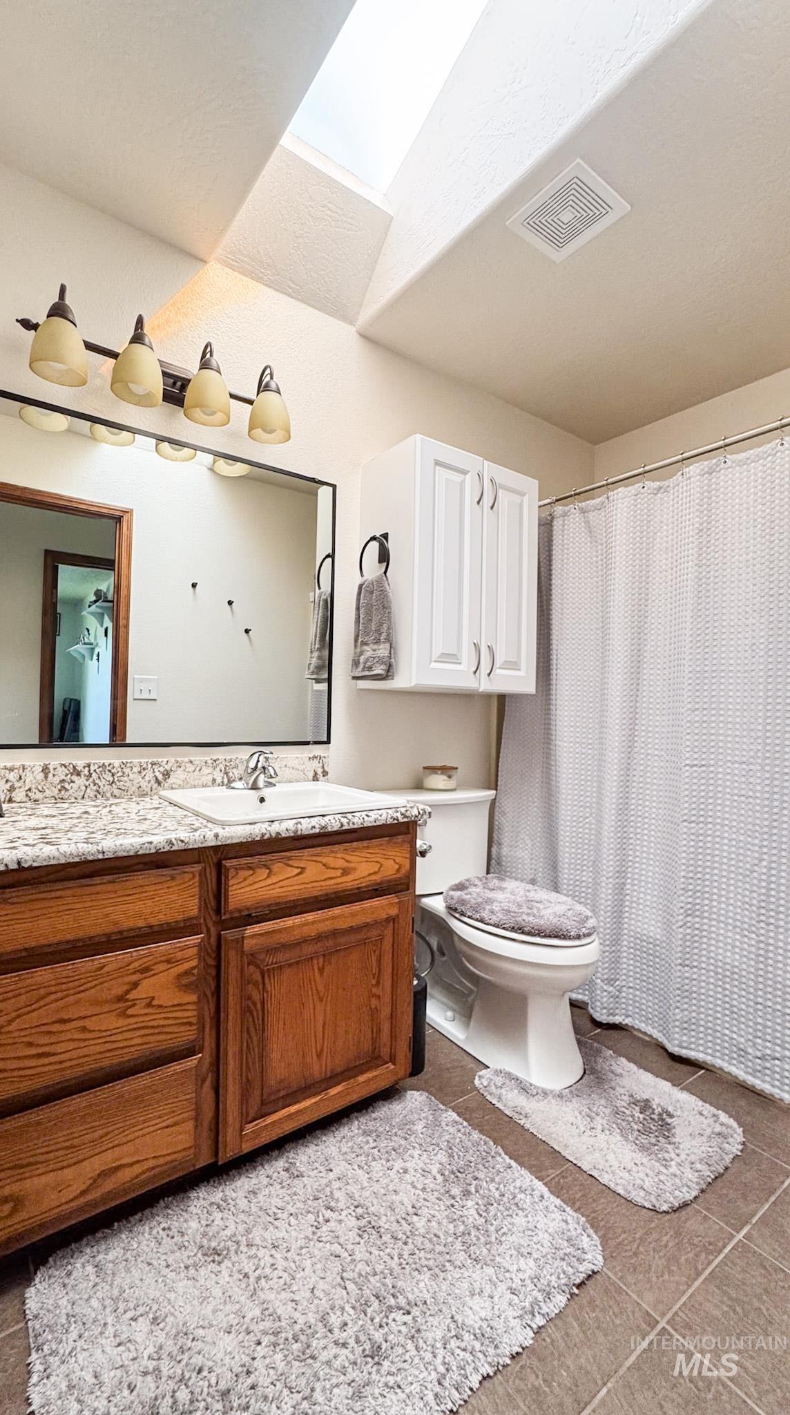 Full bath featuring vanity, dark tile patterned floors, and a shower with curtain