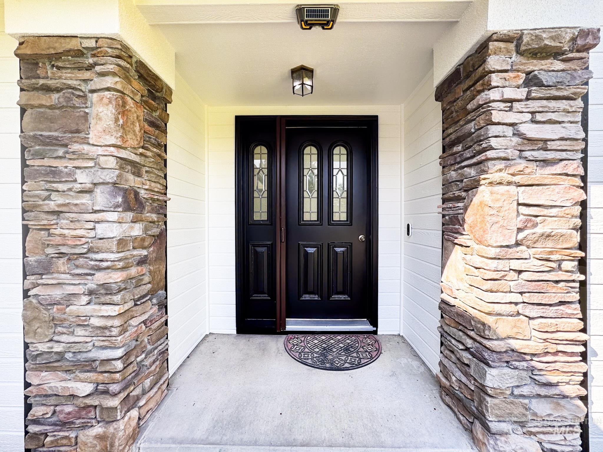 Property entrance featuring a porch and stone siding