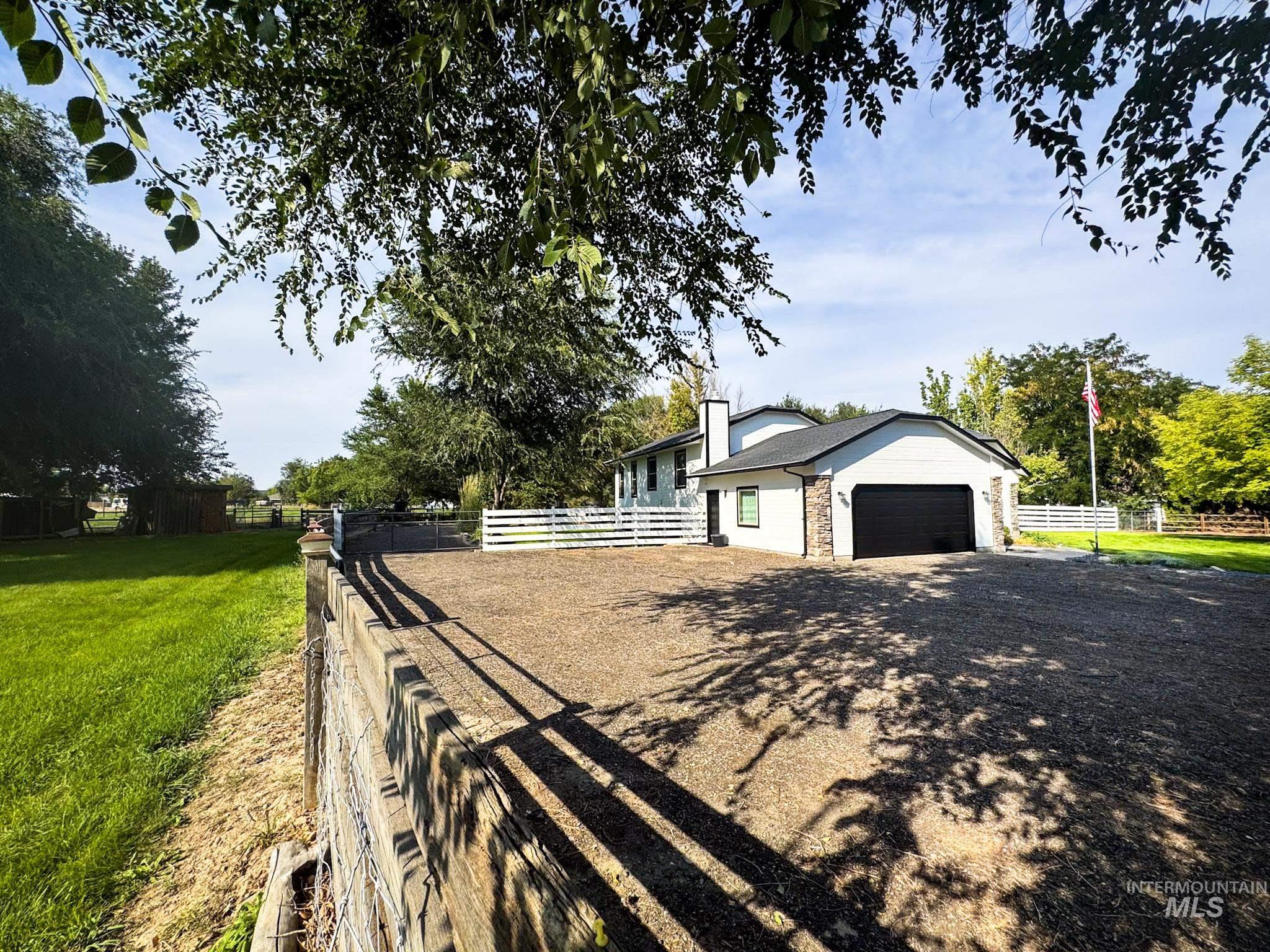 View of home's exterior featuring a garage, stone siding, driveway, and a chimney