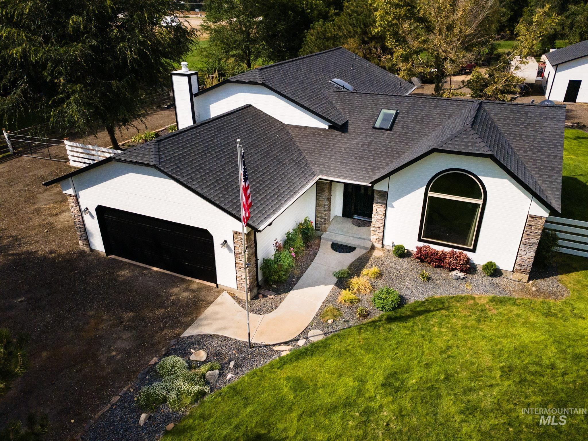 View of front of house featuring a shingled roof, an attached garage, driveway, and stone siding