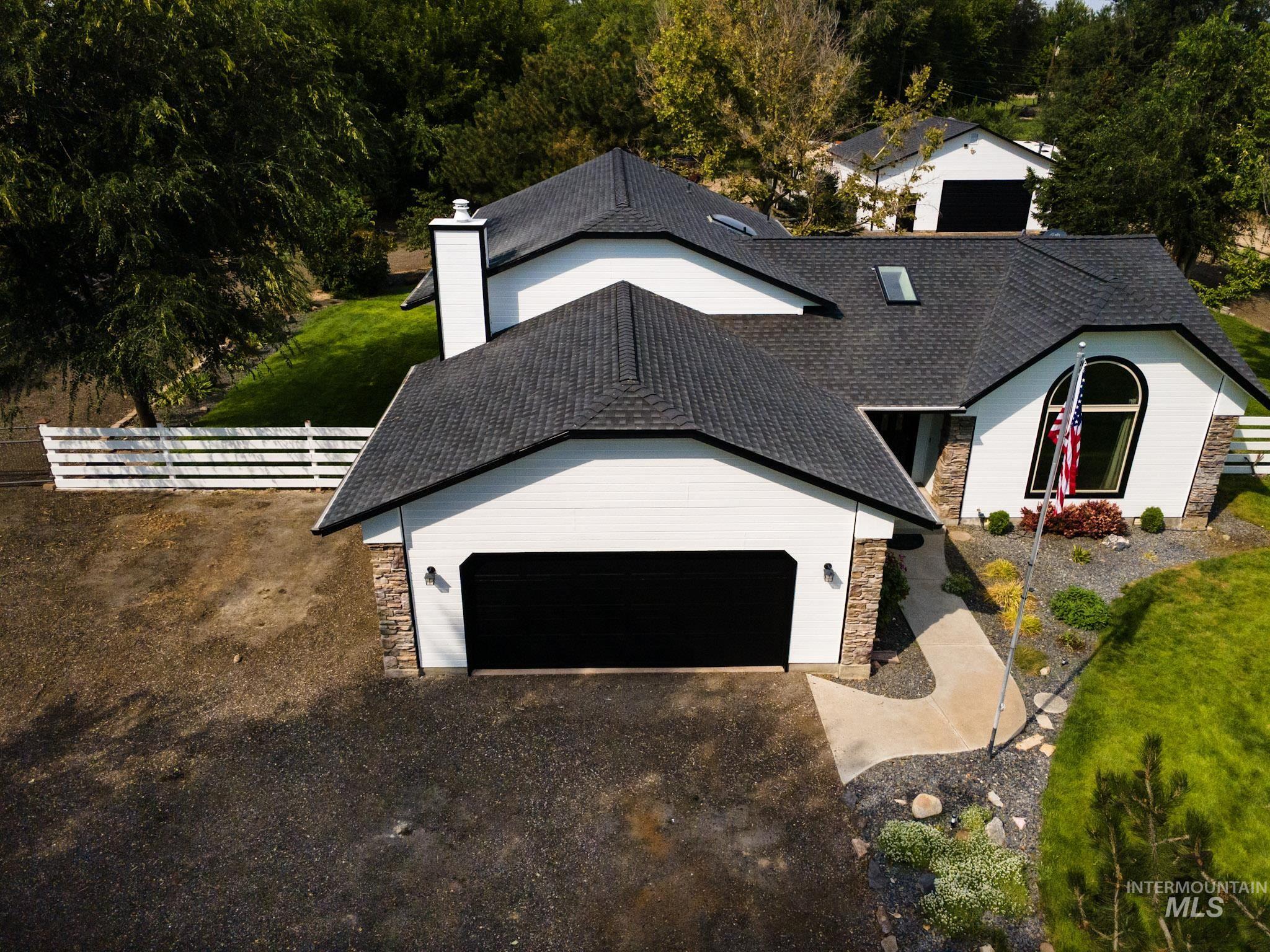 View of front of home featuring stone siding, a chimney, and roof with shingles