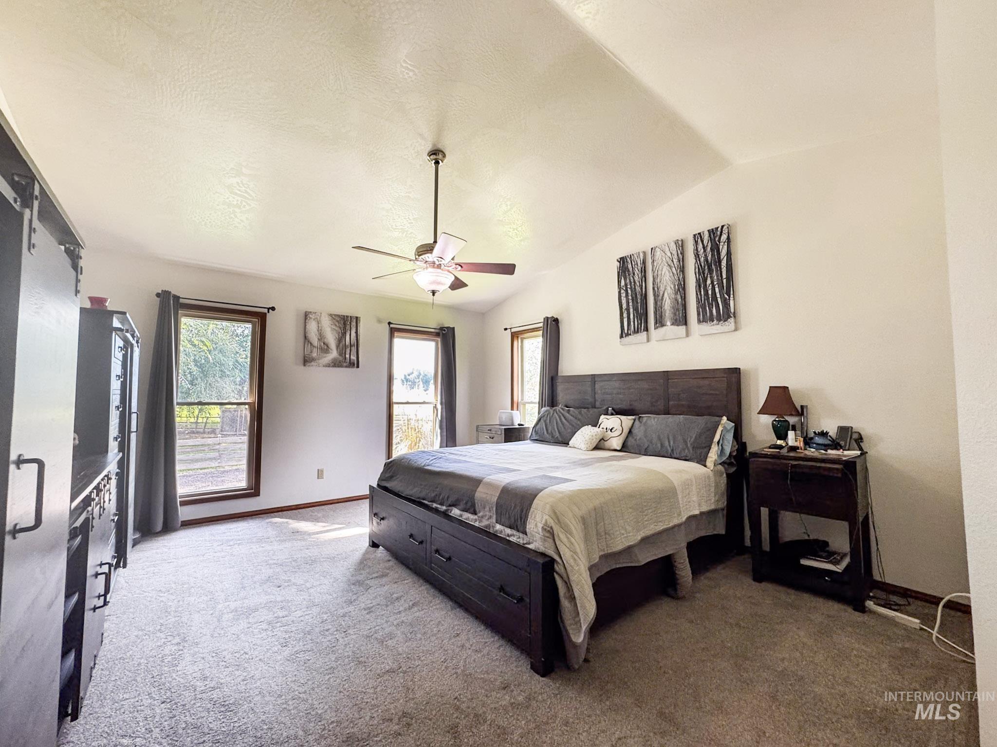 Bedroom with vaulted ceiling, carpet floors, and ceiling fan