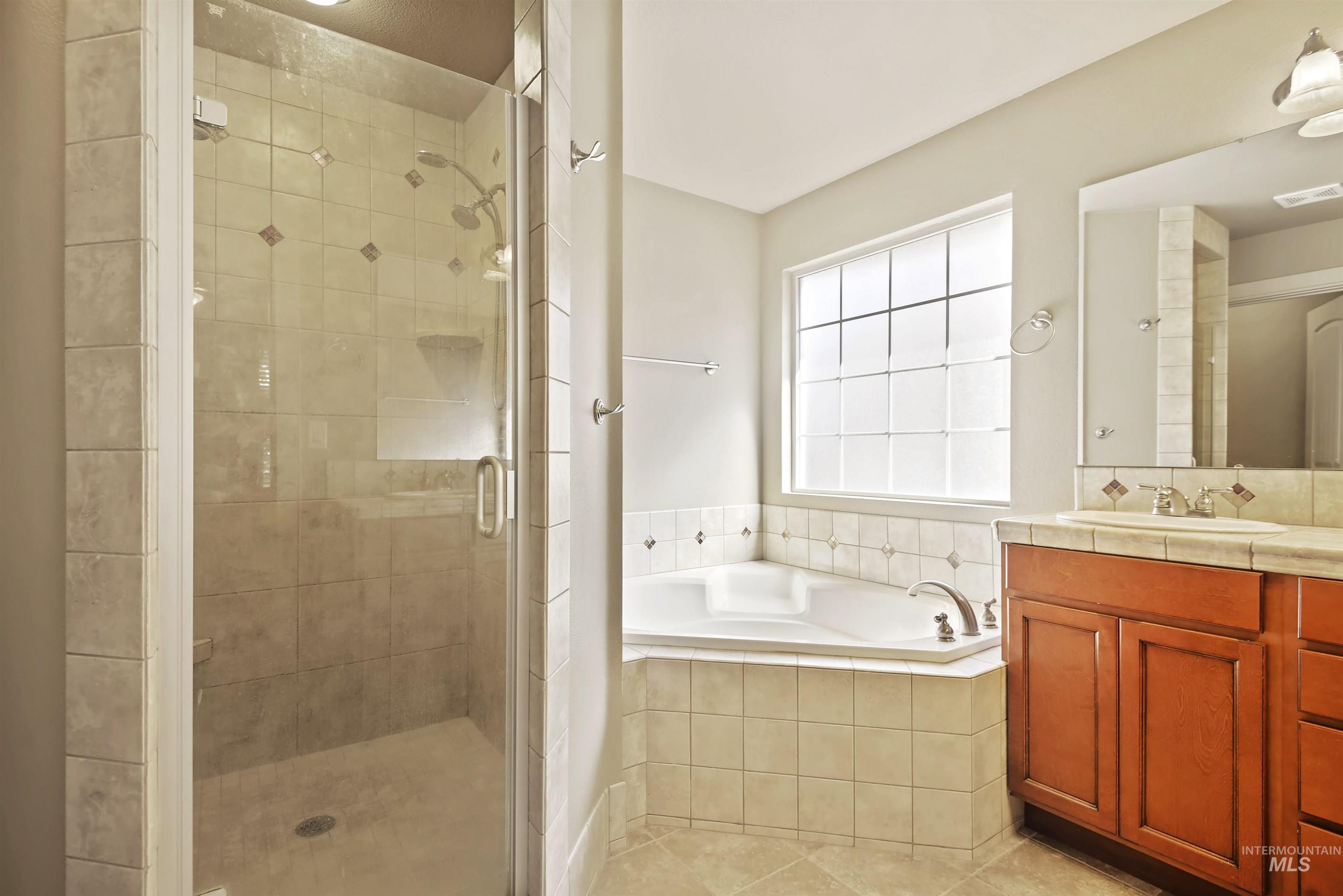 Full bath with a bath, vanity, a stall shower, and light tile patterned floors