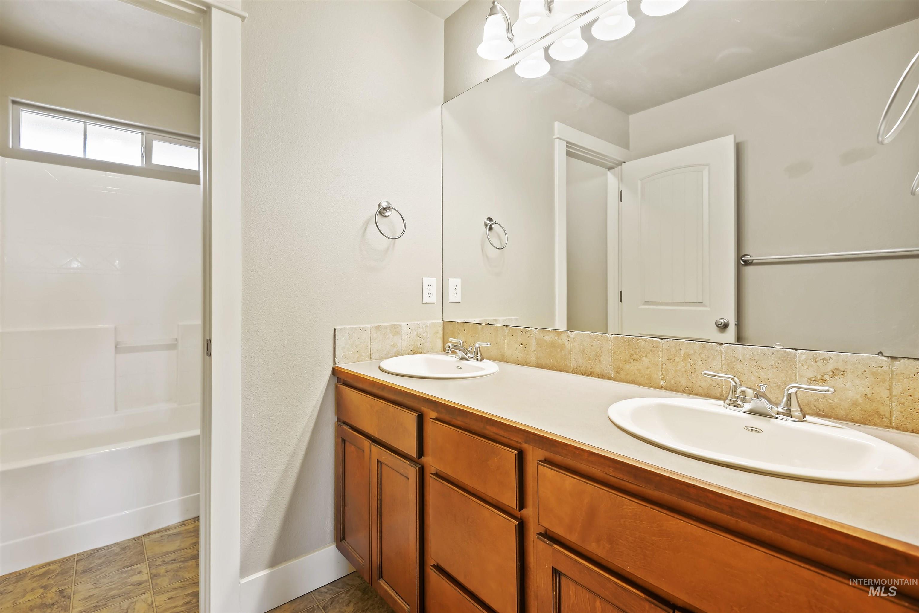 Bathroom featuring double vanity and bathing tub / shower combination