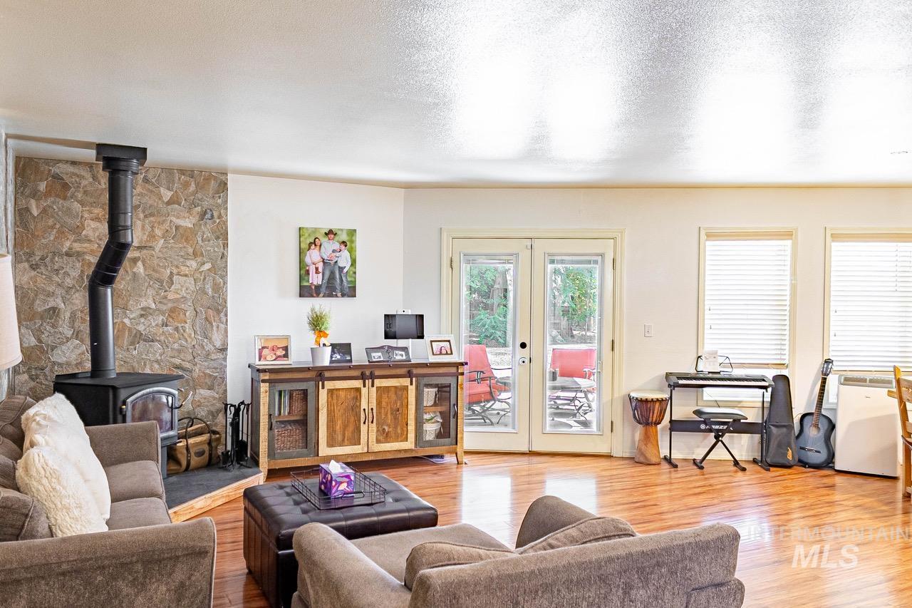 Living room with a wood stove, a textured ceiling, wood finished floors, french doors, and an office area