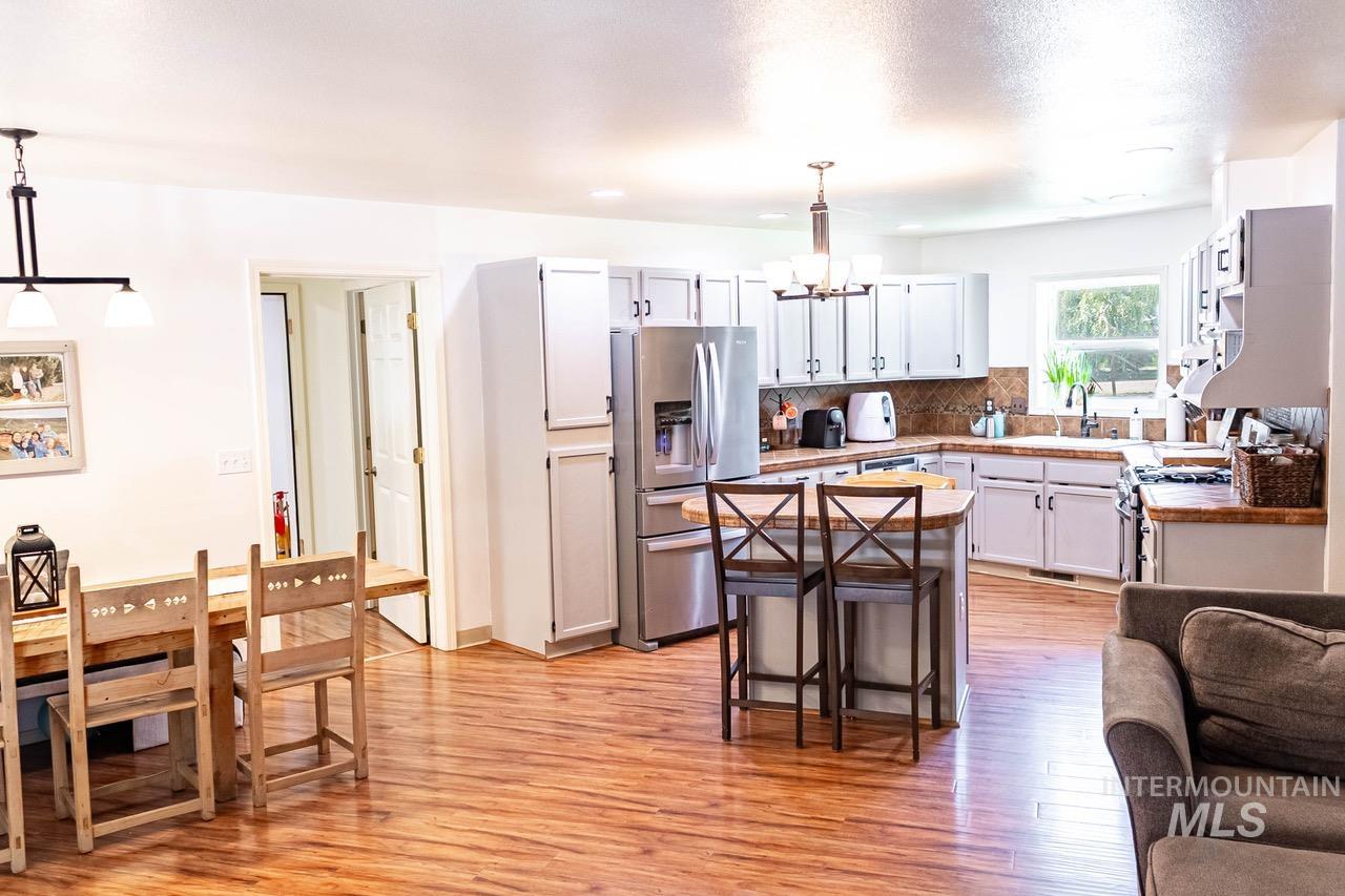 Kitchen with a chandelier, appliances with stainless steel finishes, light wood-style flooring, a kitchen island, and backsplash