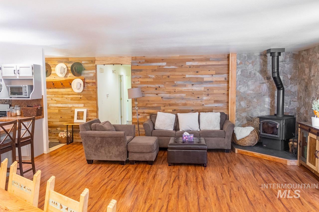 Living room featuring a wood stove, light wood-style floors, and wooden walls