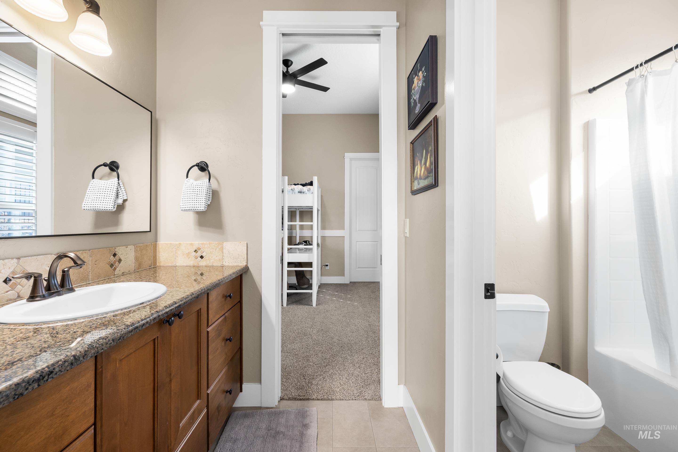 Bathroom with shower / bath combination with curtain, light tile patterned floors, light carpet, vanity, and ceiling fan