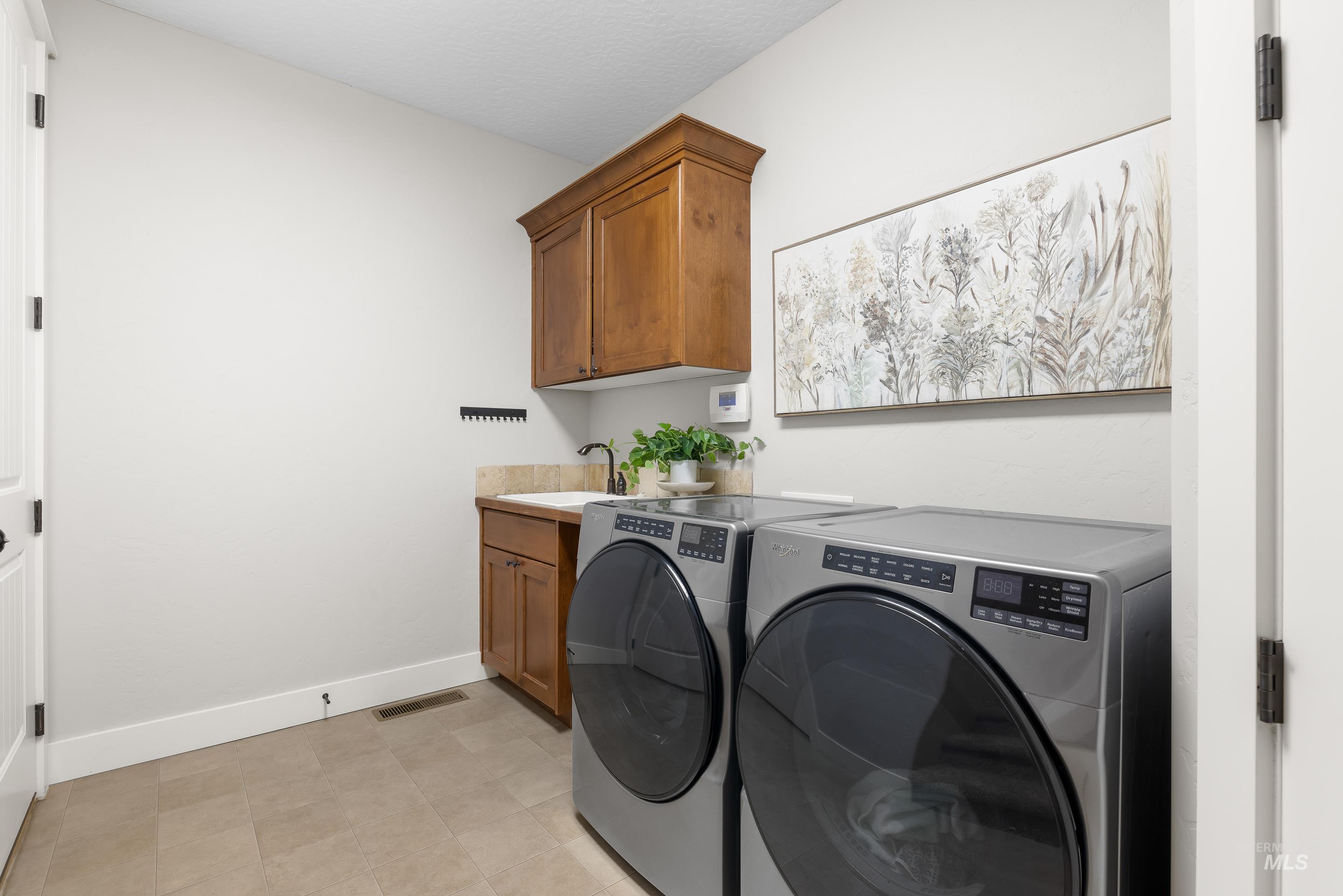 Laundry area featuring separate washer and dryer and cabinet space