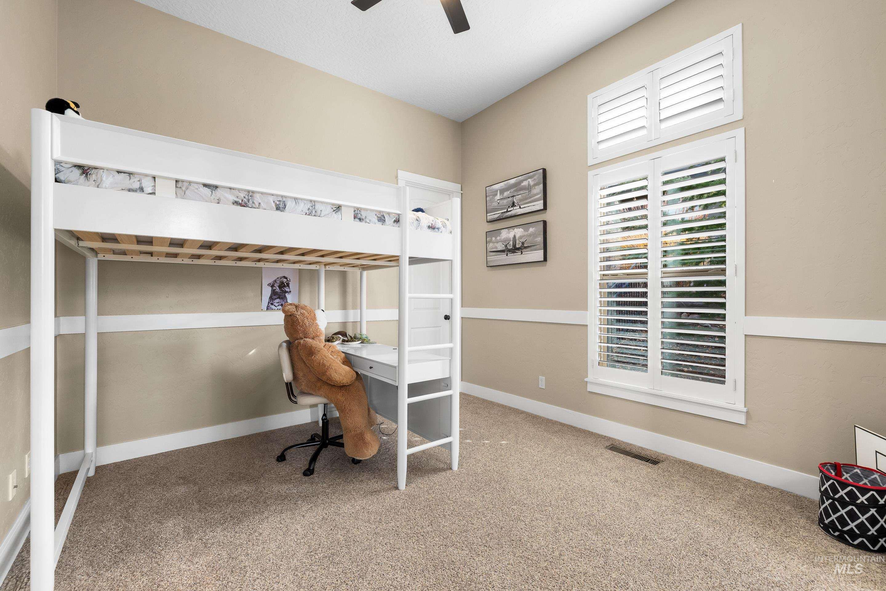 Carpeted bedroom featuring ceiling fan and a desk