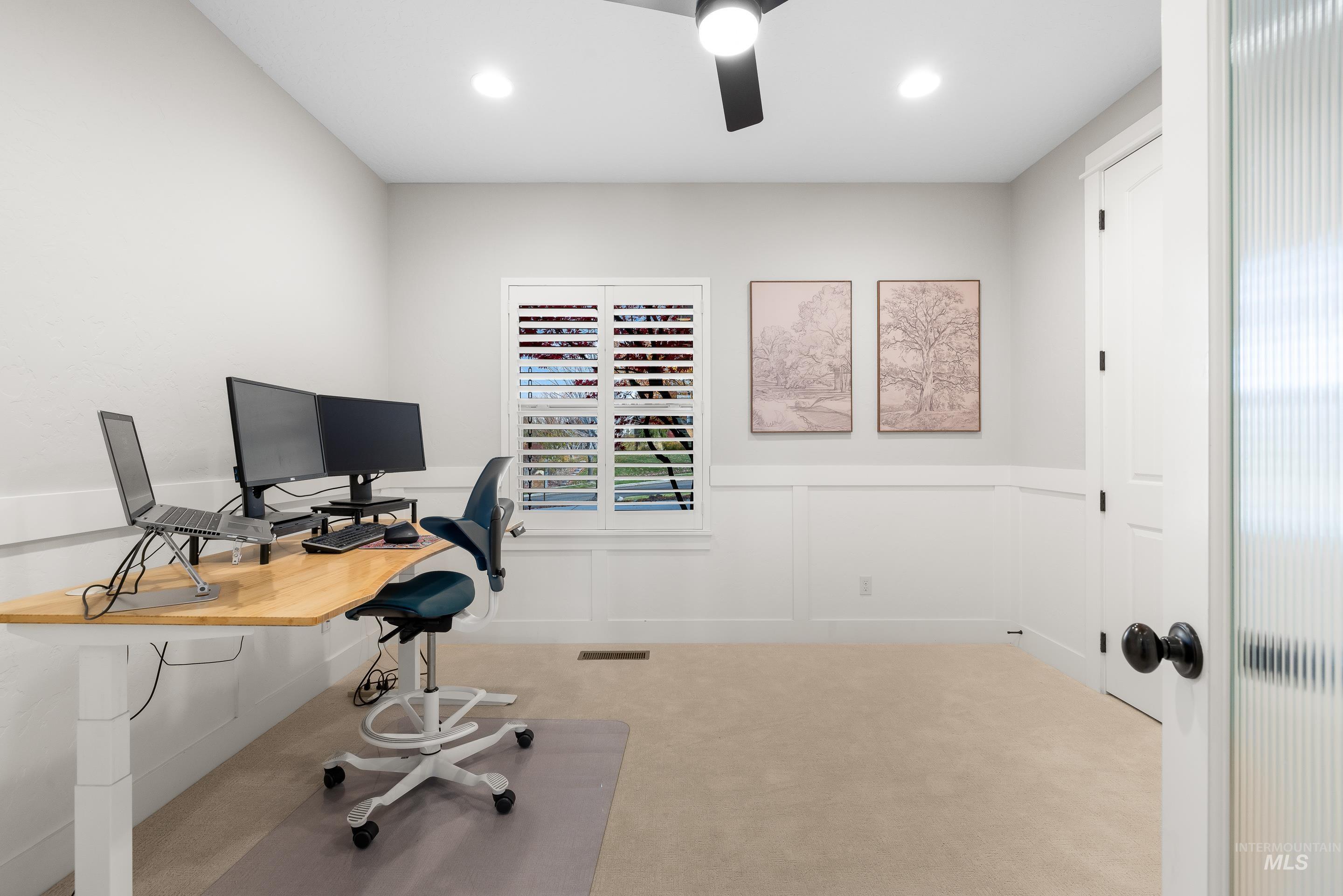Carpeted office space with a decorative wall, a wainscoted wall, recessed lighting, and a ceiling fan