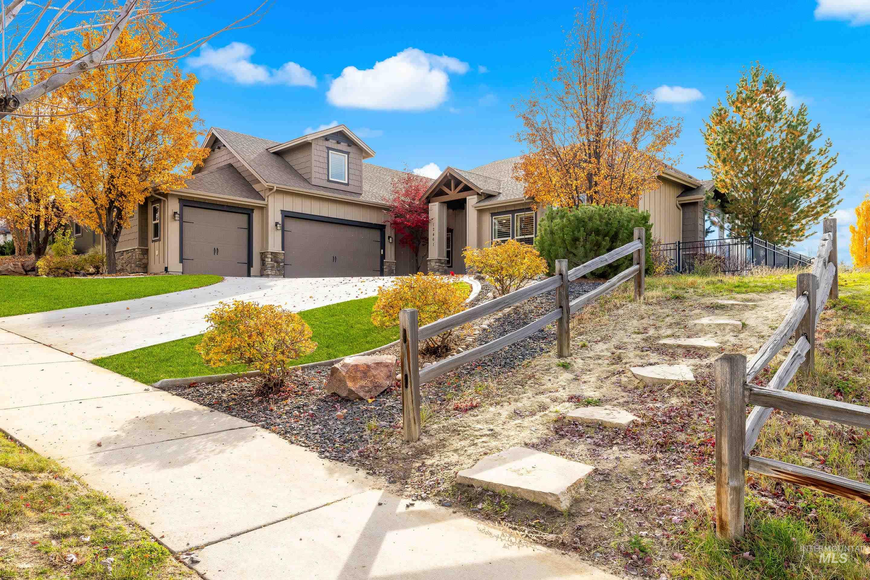 View of front facade featuring concrete driveway, stone siding, roof with shingles, and a garage
