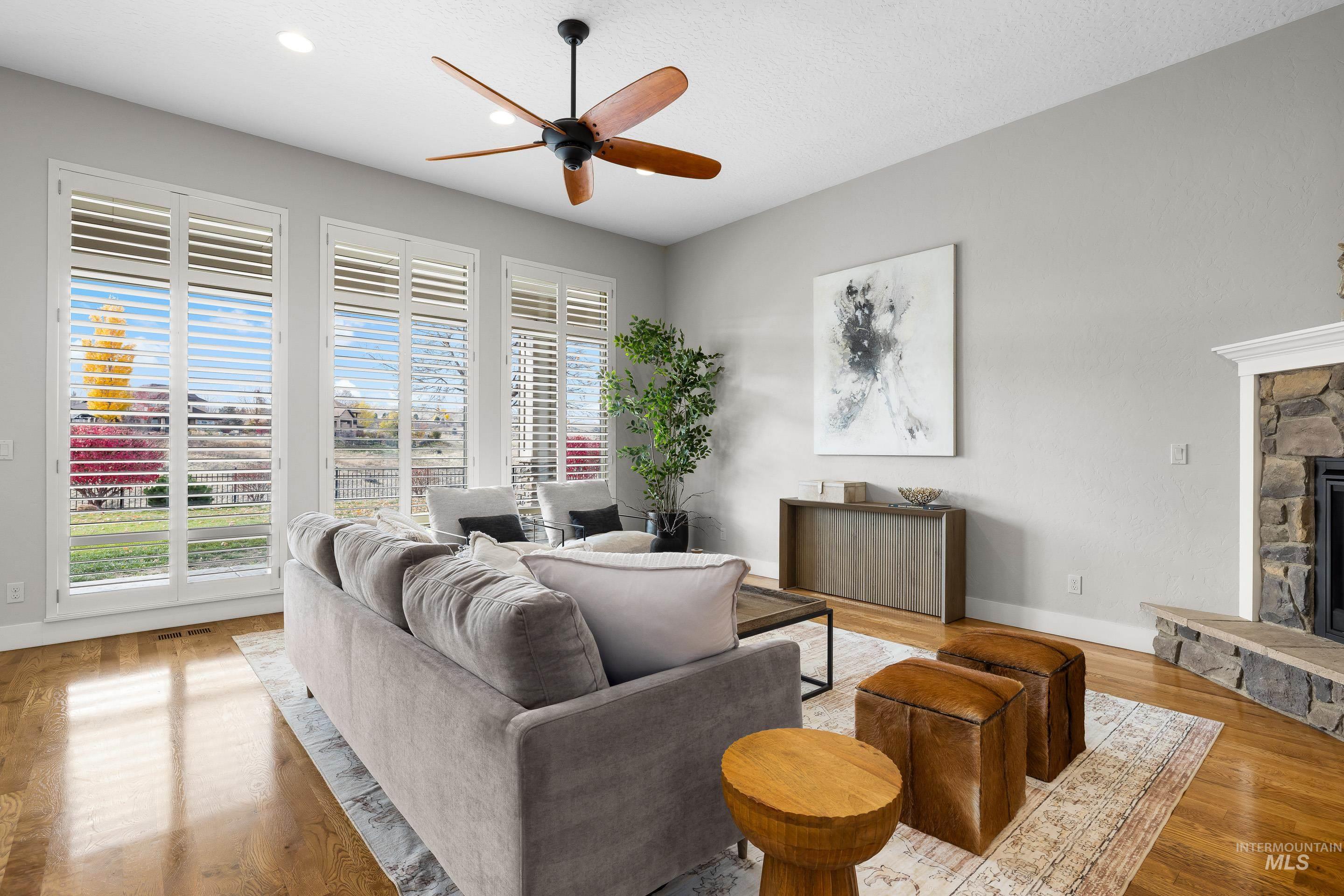 Living room featuring light wood-style flooring, ceiling fan, a fireplace, recessed lighting, and a textured ceiling
