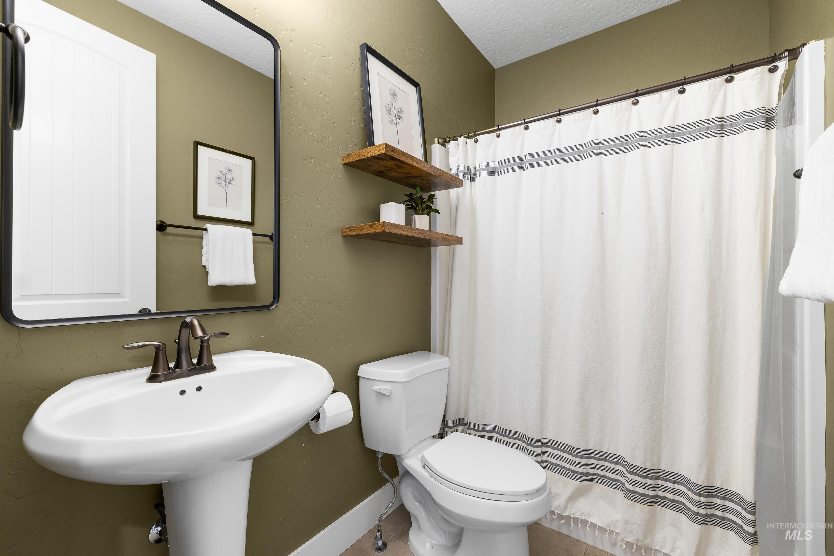 Full bathroom featuring a shower with curtain, a textured ceiling, and a textured wall