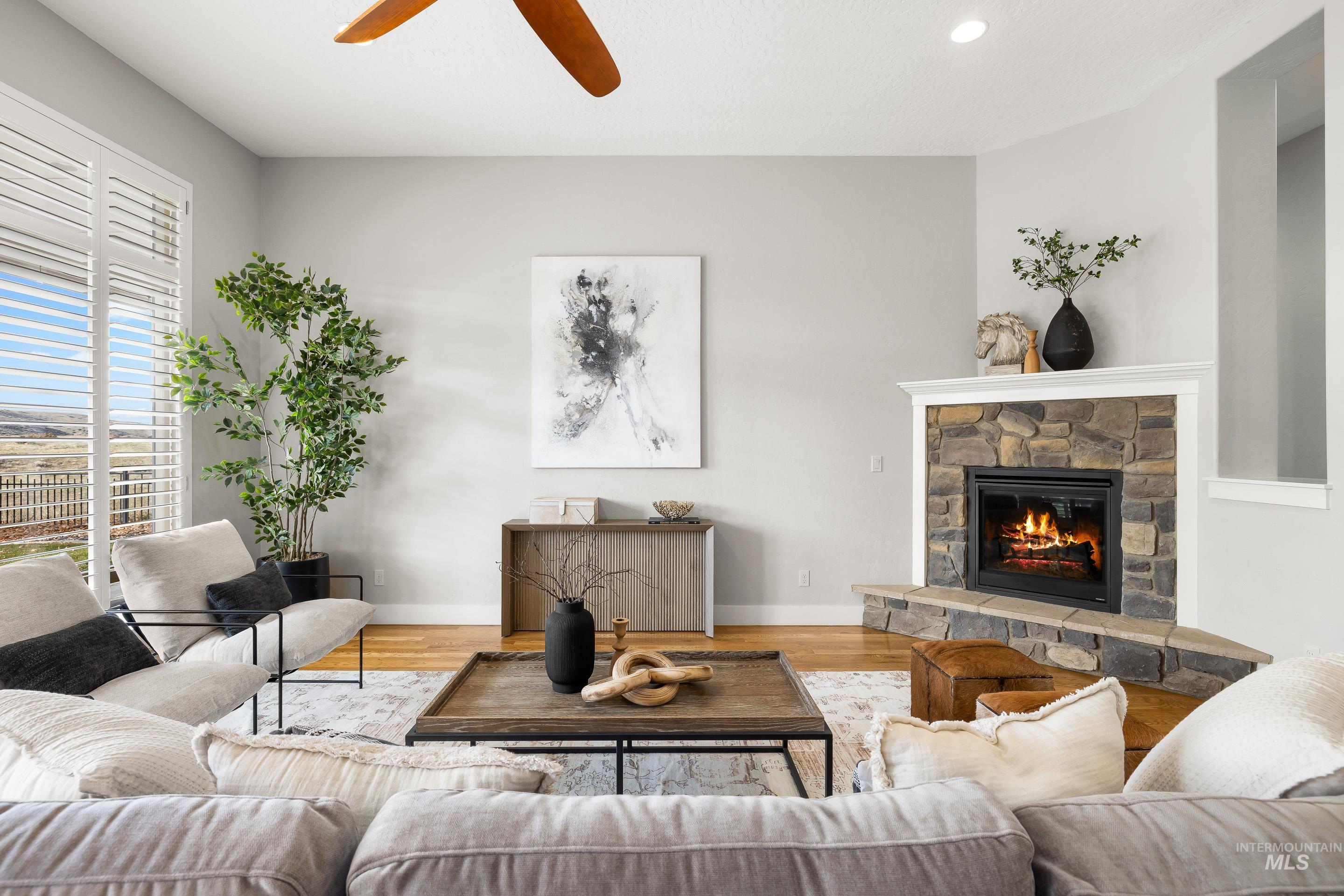 Living room with a fireplace, wood finished floors, a ceiling fan, and recessed lighting