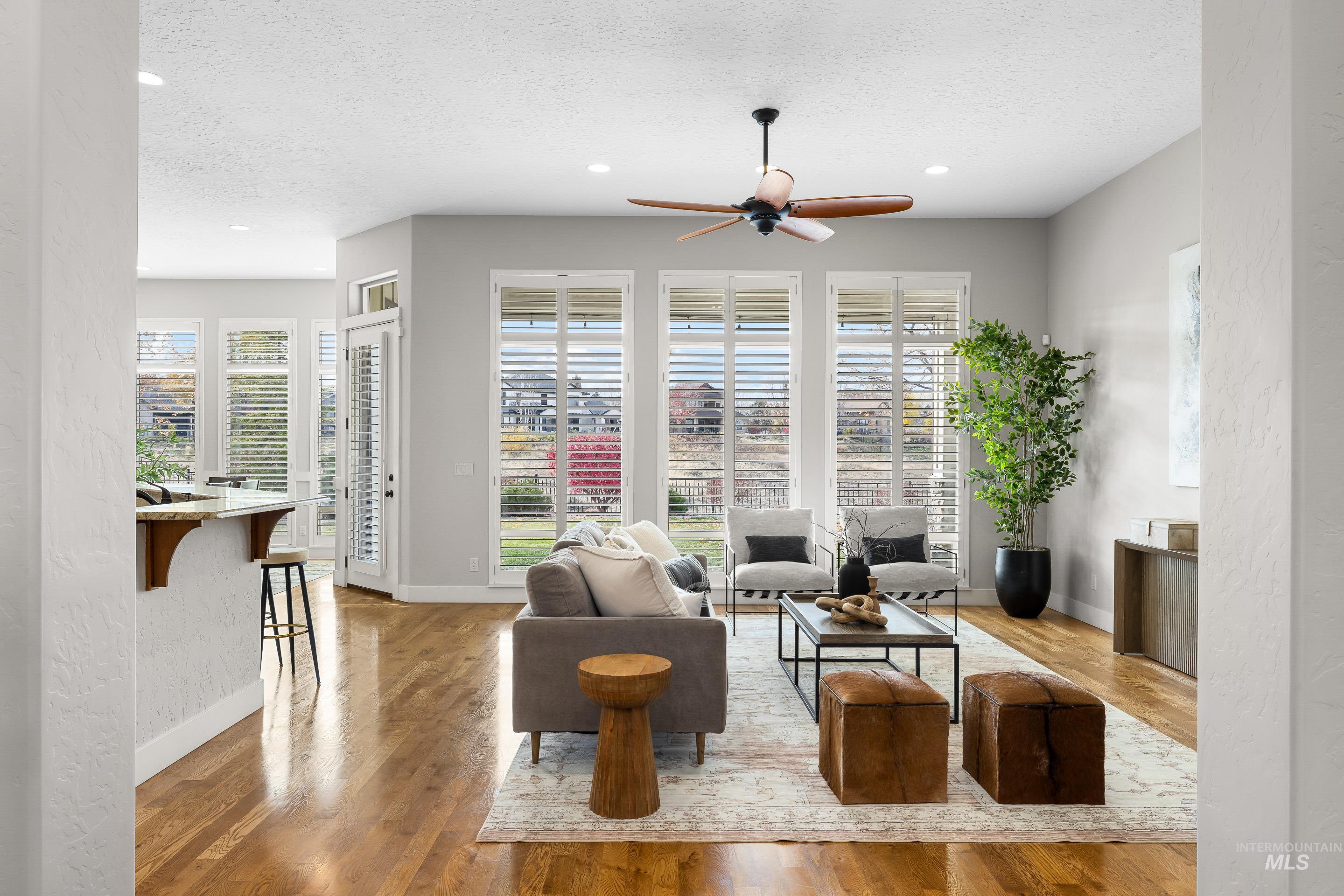 Living area with healthy amount of natural light, light wood-style flooring, a textured ceiling, a ceiling fan, and recessed lighting