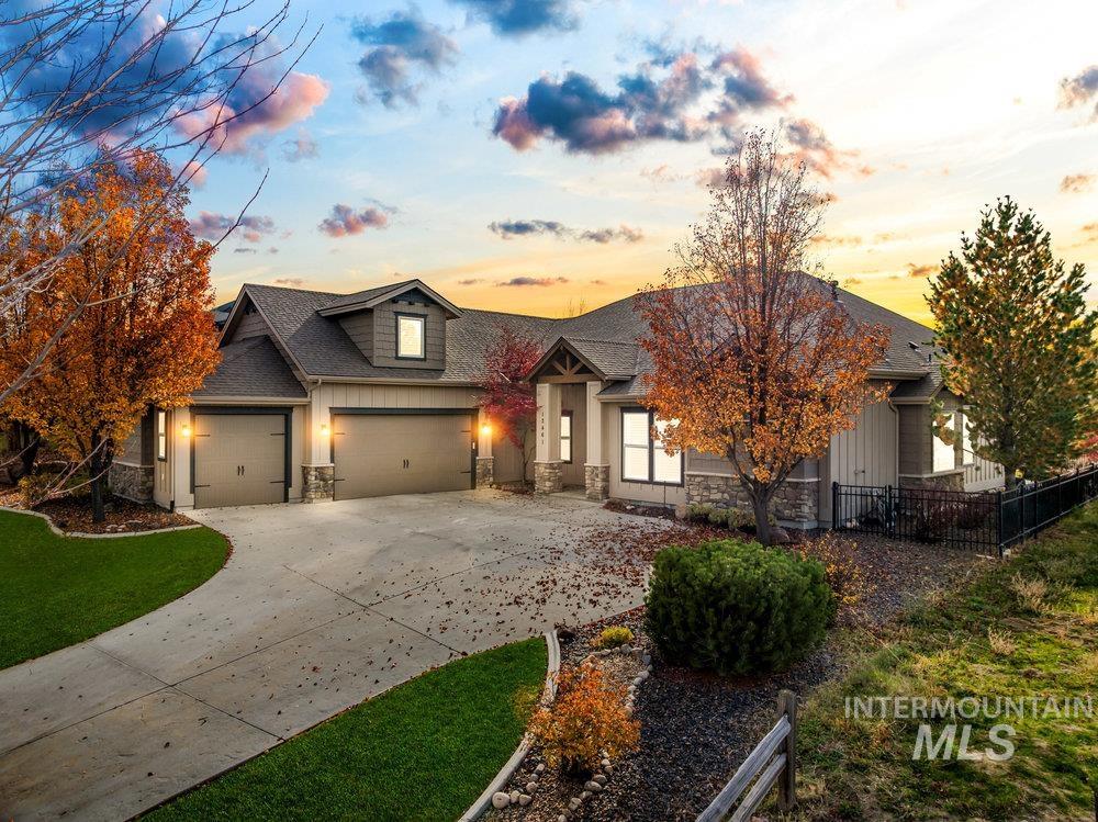 View of front of property with stone siding, concrete driveway, roof with shingles, and an attached garage