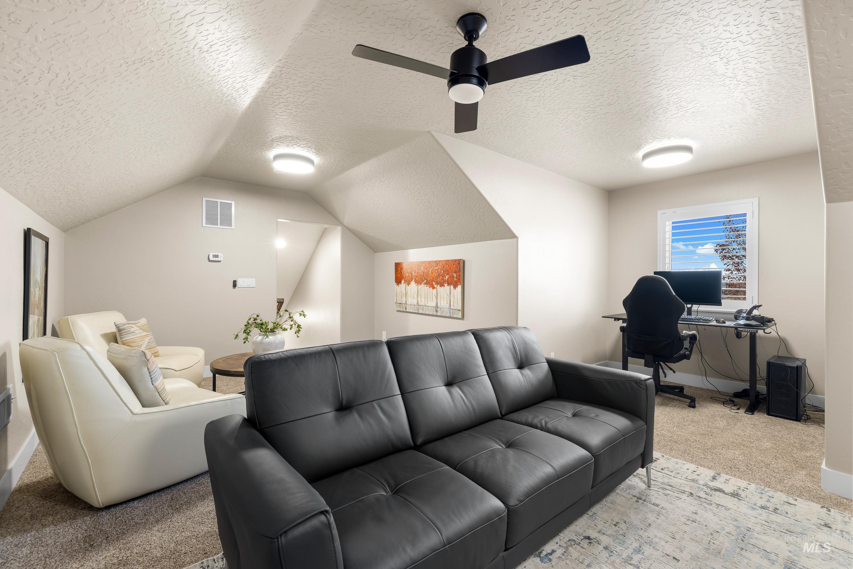 Home theater featuring a textured ceiling, carpet, lofted ceiling, and a ceiling fan