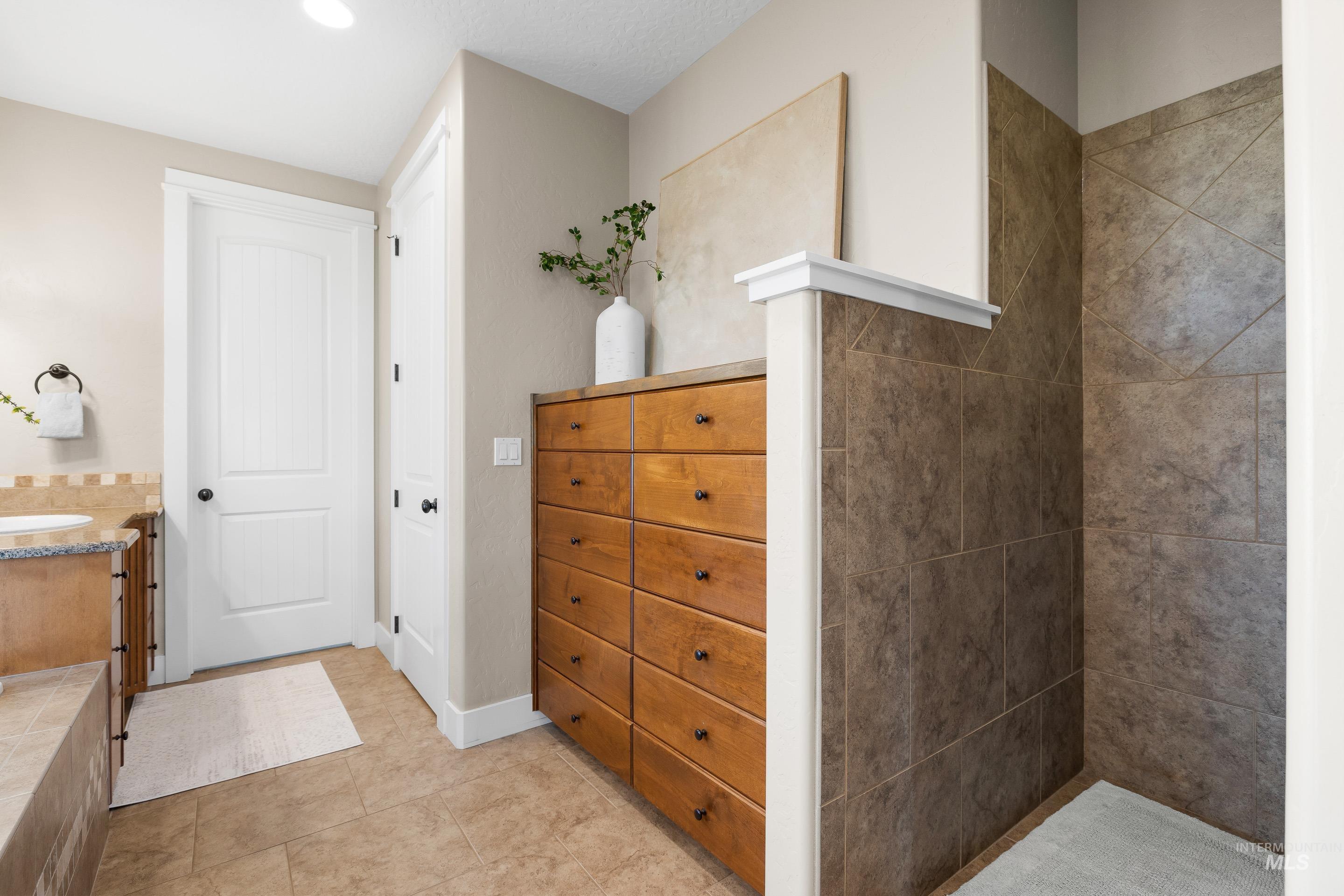 Bathroom with vanity, light tile patterned floors, a tile shower, and recessed lighting