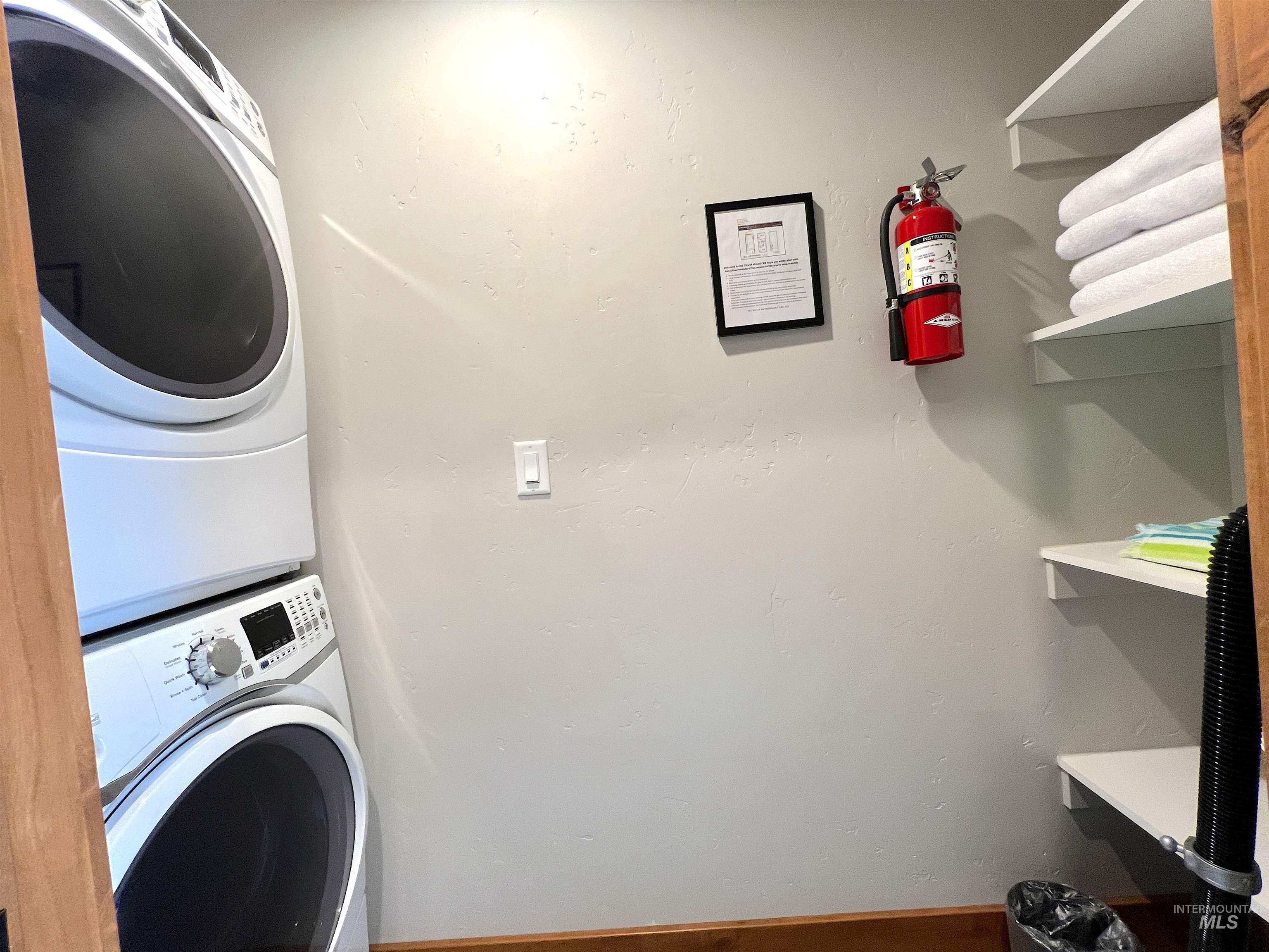 Washroom with stacked washing machine and dryer and baseboards
