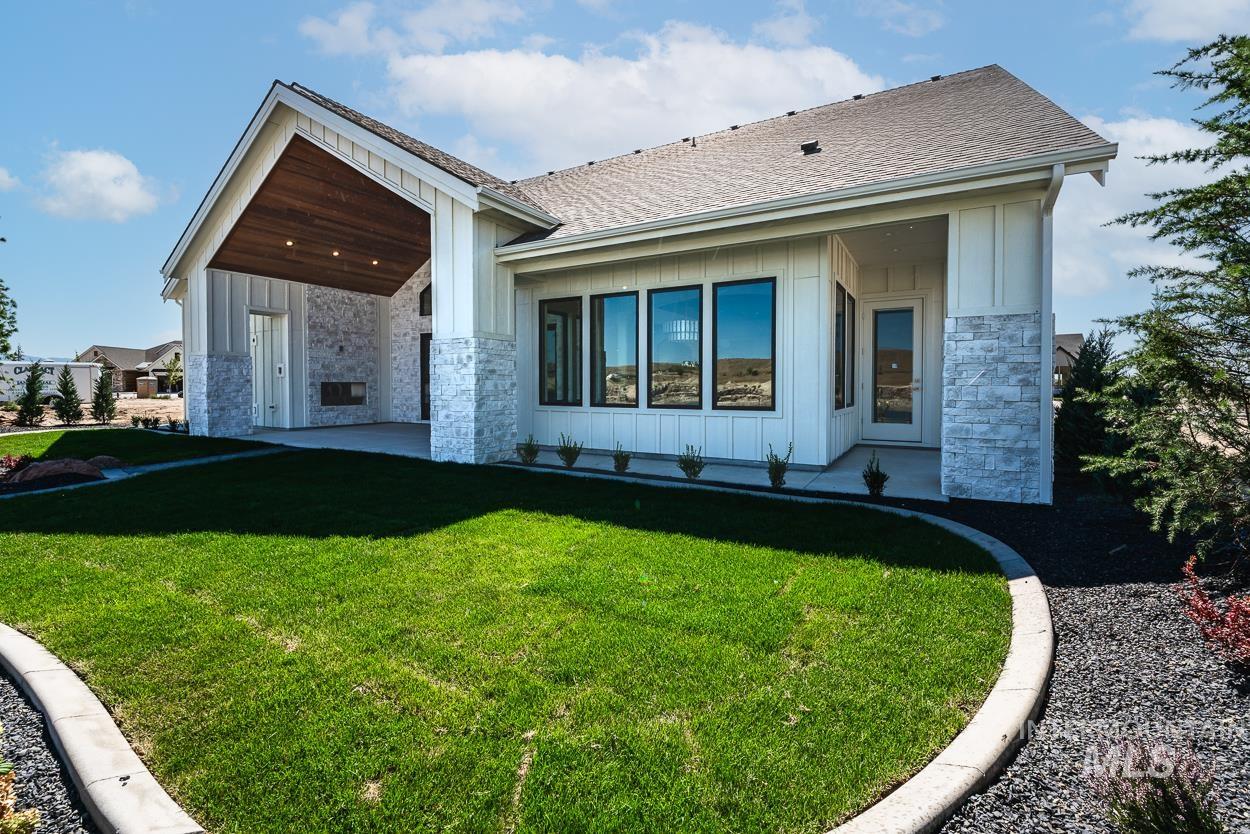 View of front of home with board and batten siding, stone siding, and a patio area