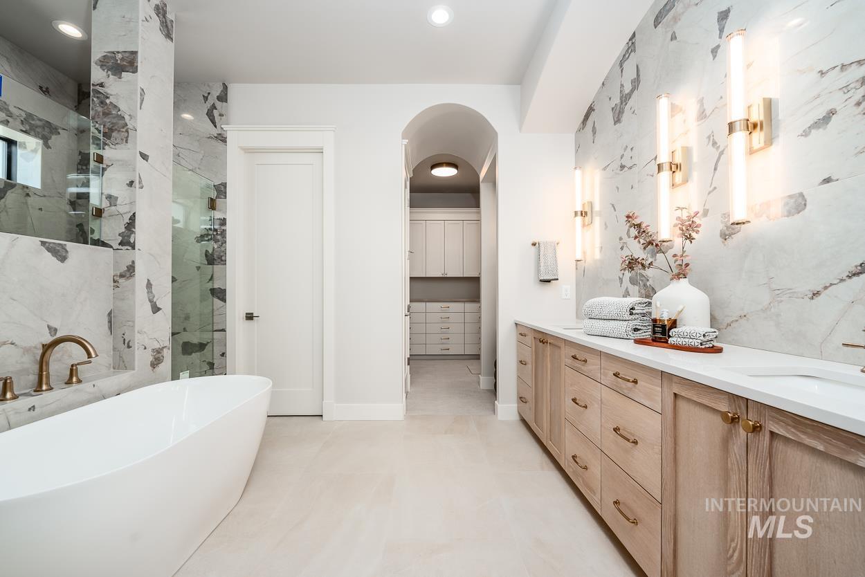 Bathroom with a marble finish shower, double vanity, a freestanding tub, and recessed lighting