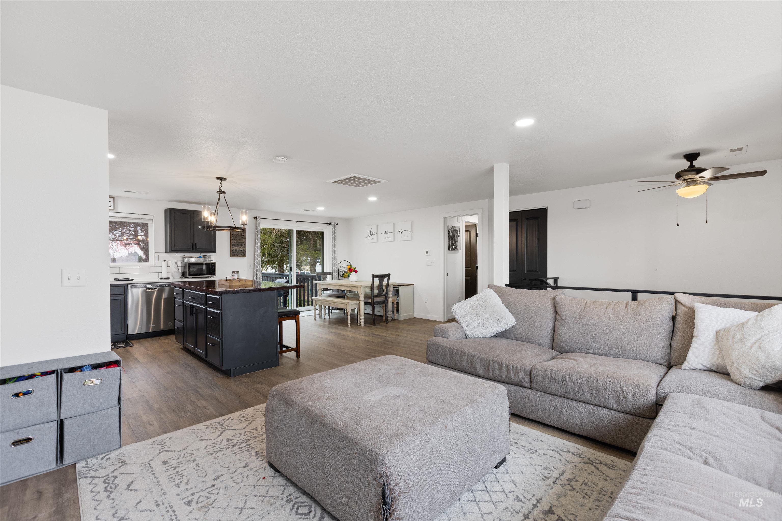Living area featuring dark wood-style flooring, a ceiling fan, and a chandelier