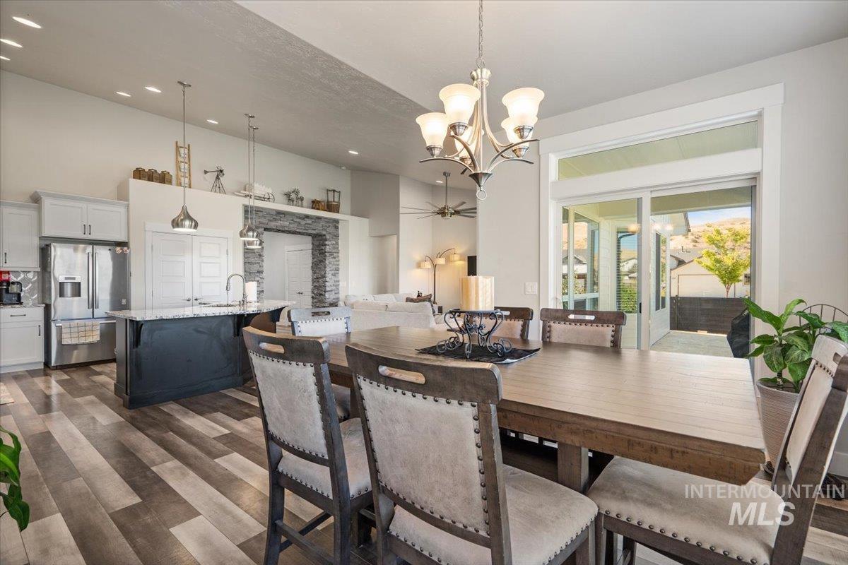 Dining space with dark wood-style floors, a chandelier, recessed lighting, and a towering ceiling