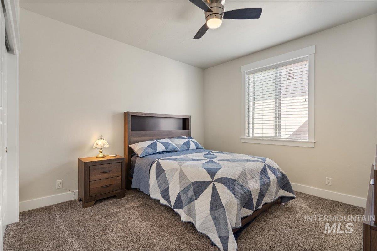 Carpeted bedroom featuring baseboards and ceiling fan