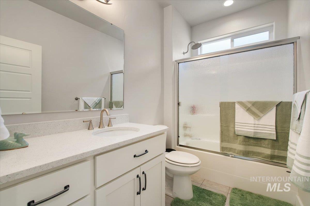 Bathroom featuring combined bath / shower with glass door, vanity, and light tile patterned floors