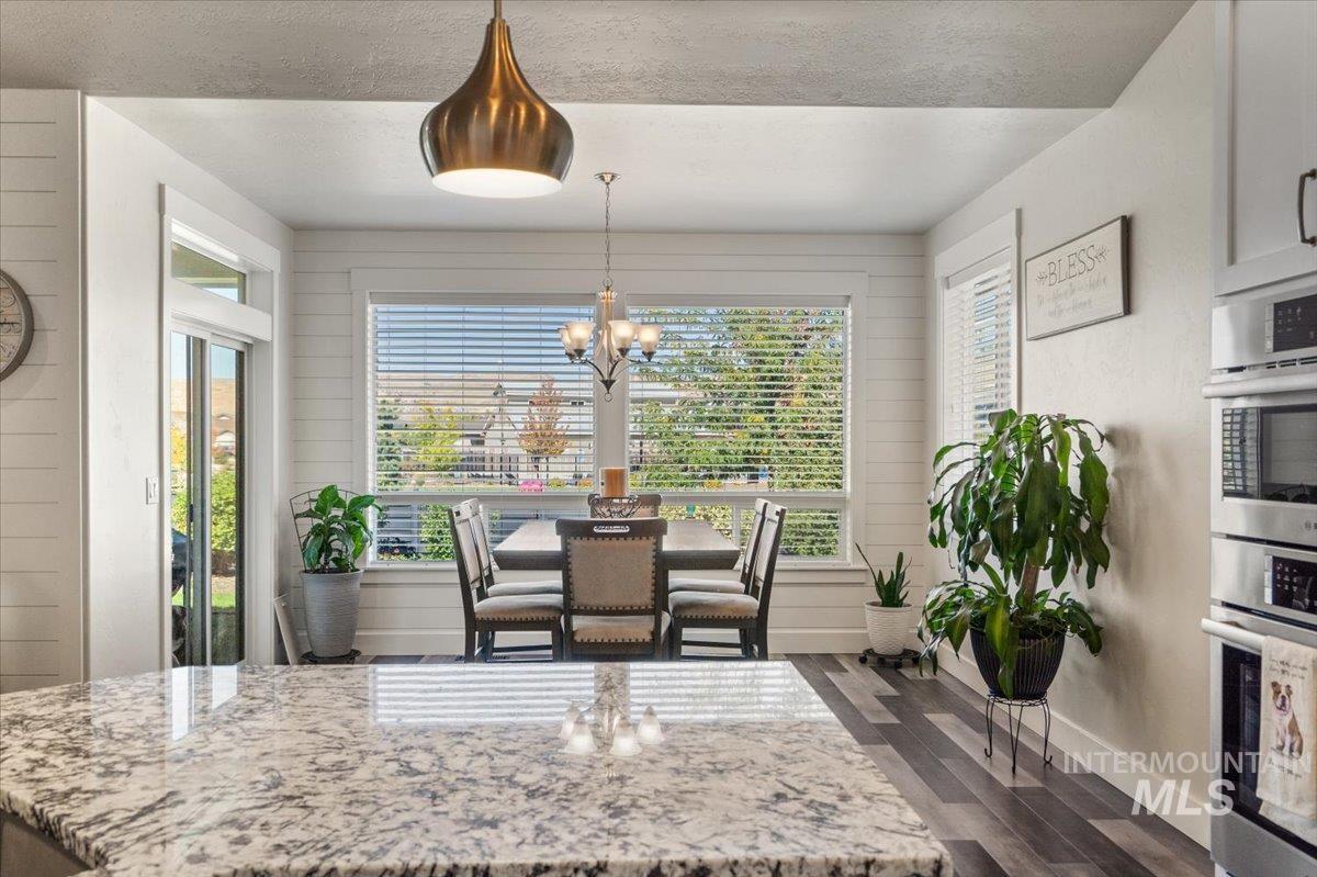 Dining area with a chandelier, dark wood-style flooring, wooden walls, and a textured ceiling