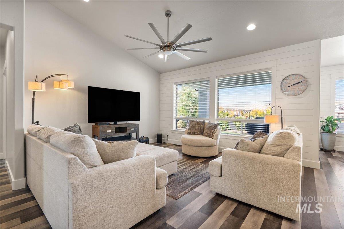 Living area featuring lofted ceiling, healthy amount of natural light, recessed lighting, dark wood finished floors, and a ceiling fan
