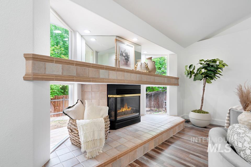 Living room with lofted ceiling, healthy amount of natural light, wood finished floors, a fireplace, and recessed lighting