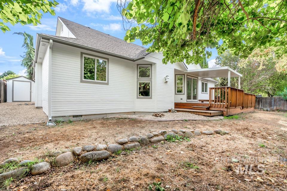 Rear view of house with a wooden deck, a shed, and roof with shingles