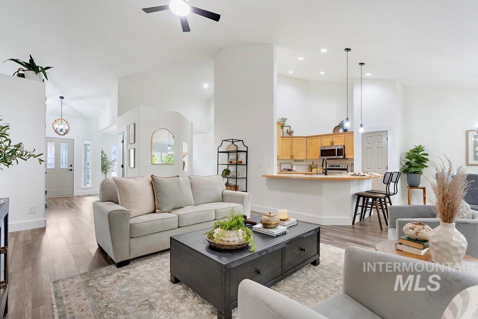 Living area featuring high vaulted ceiling, wood finished floors, recessed lighting, and ceiling fan
