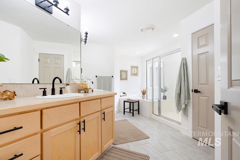 Full bathroom featuring double vanity, a shower stall, a garden tub, light tile patterned floors, and recessed lighting