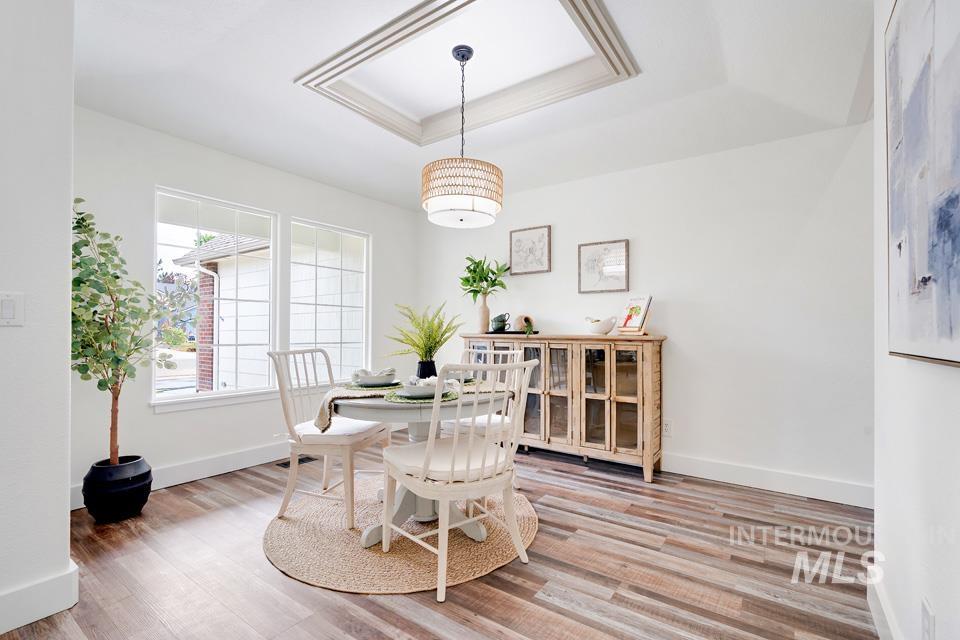 Dining space with light wood-style flooring and a tray ceiling