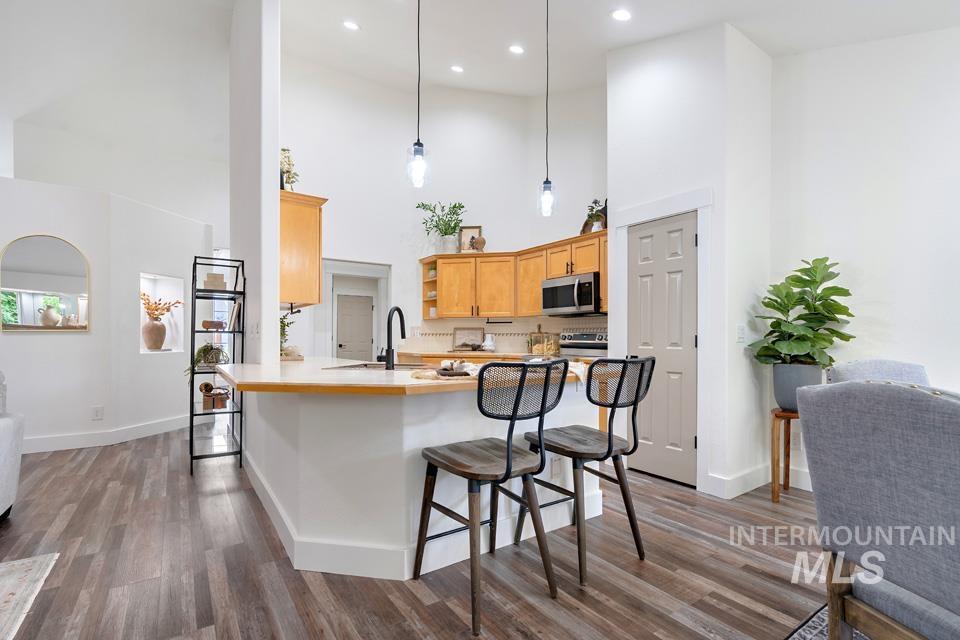 Kitchen featuring light countertops, a kitchen bar, a peninsula, dark wood-type flooring, and open shelves