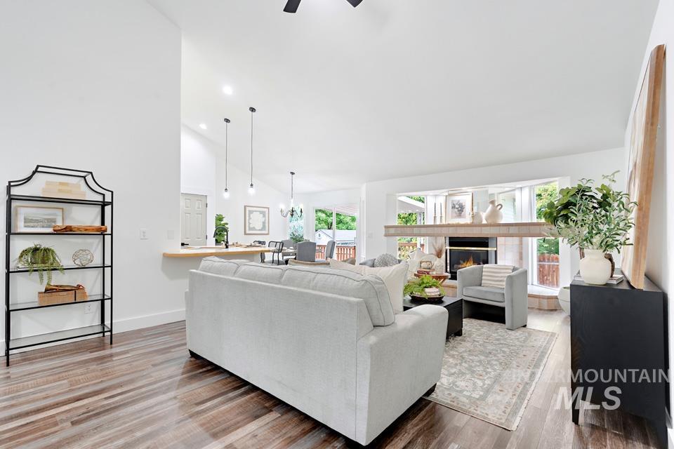 Living room featuring high vaulted ceiling, a tiled fireplace, wood finished floors, ceiling fan, and recessed lighting