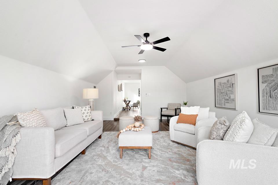 Living room featuring lofted ceiling, wood finished floors, and ceiling fan